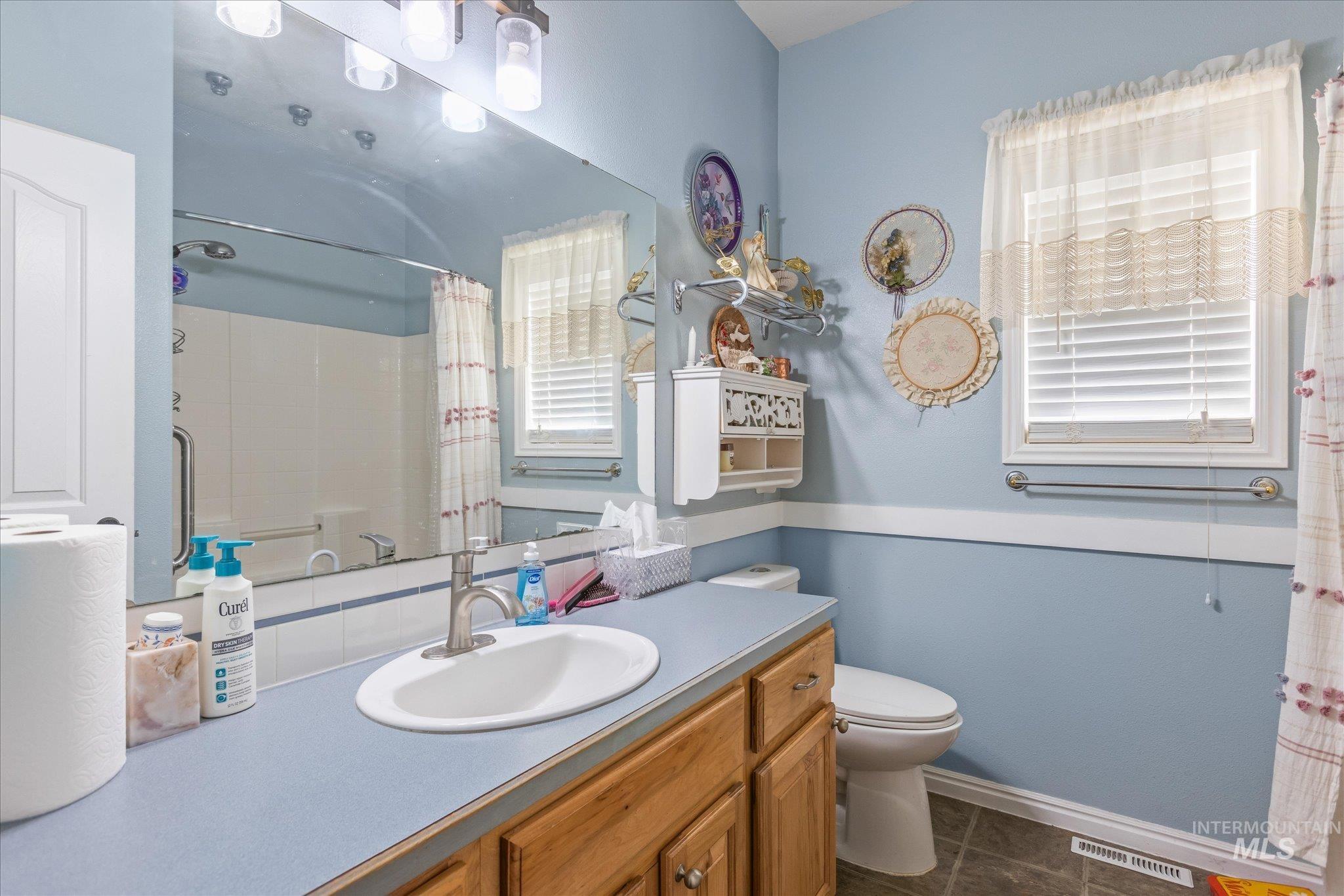 Bathroom with a shower with curtain, vanity, and dark tile patterned floors
