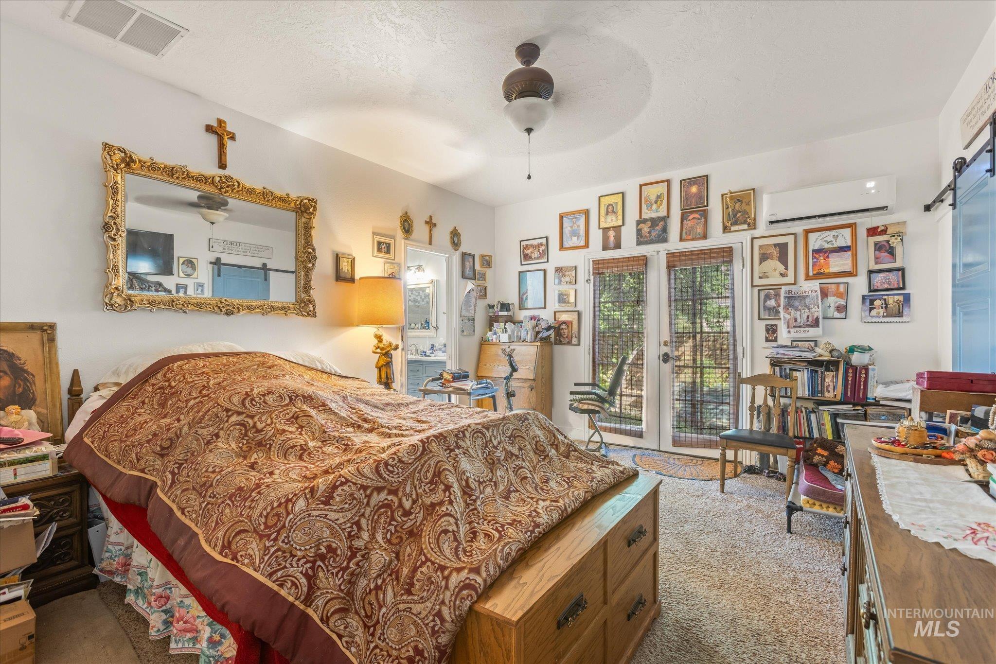 Bedroom with french doors, light colored carpet, a barn door, access to exterior, and a ceiling fan