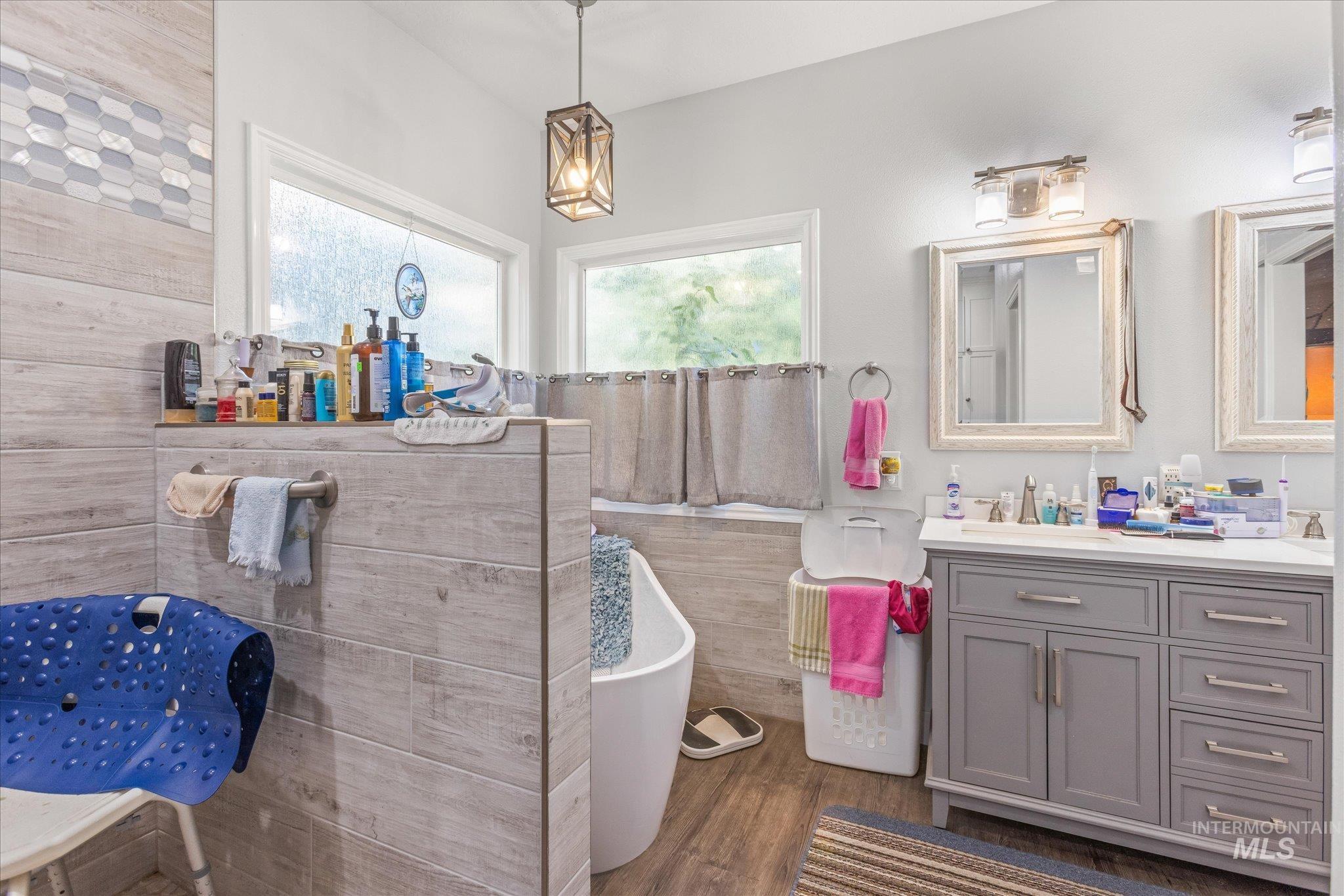 Bathroom featuring vanity, dark wood finished floors, a soaking tub, and tile walls