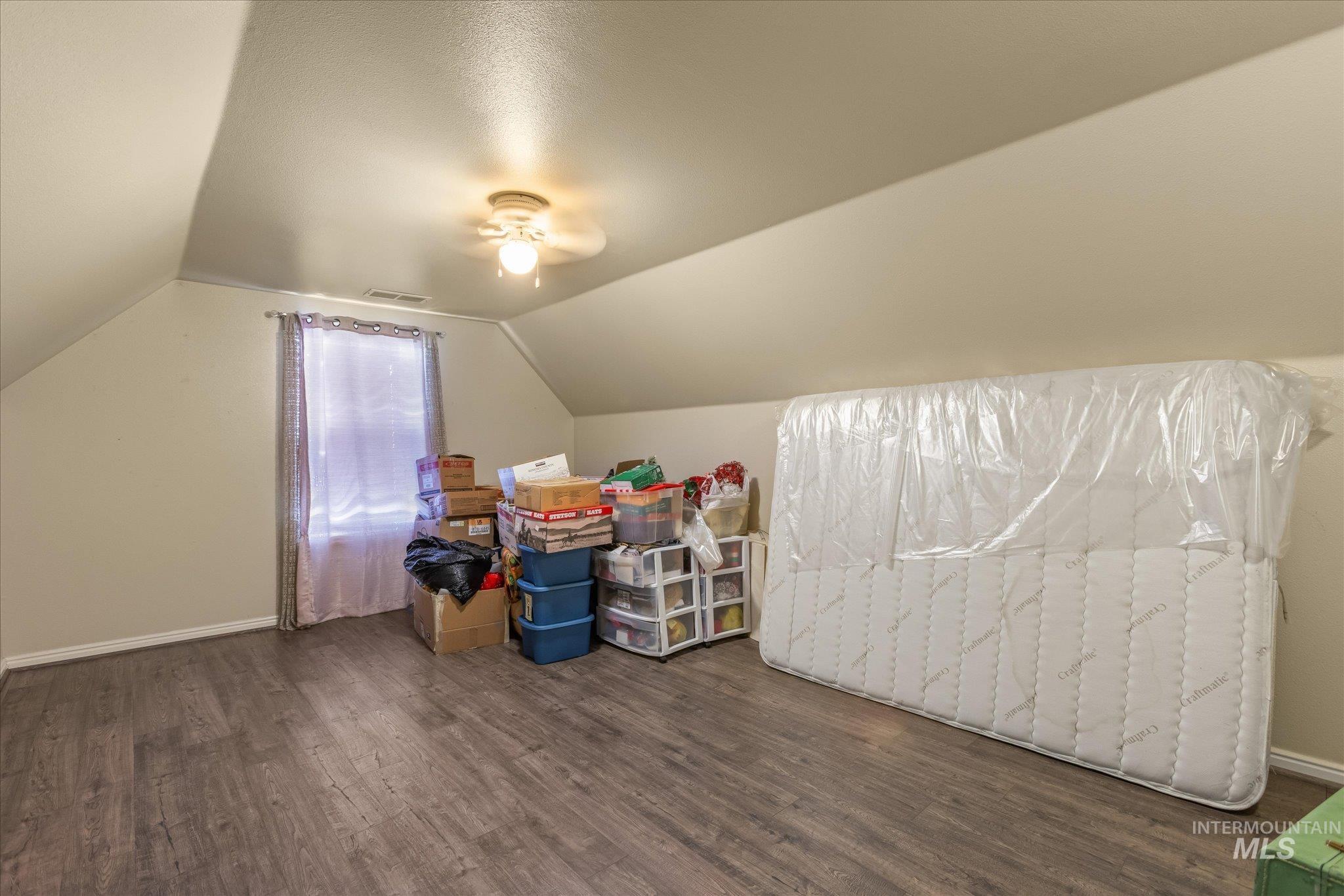 Additional living space featuring vaulted ceiling and dark wood finished floors
