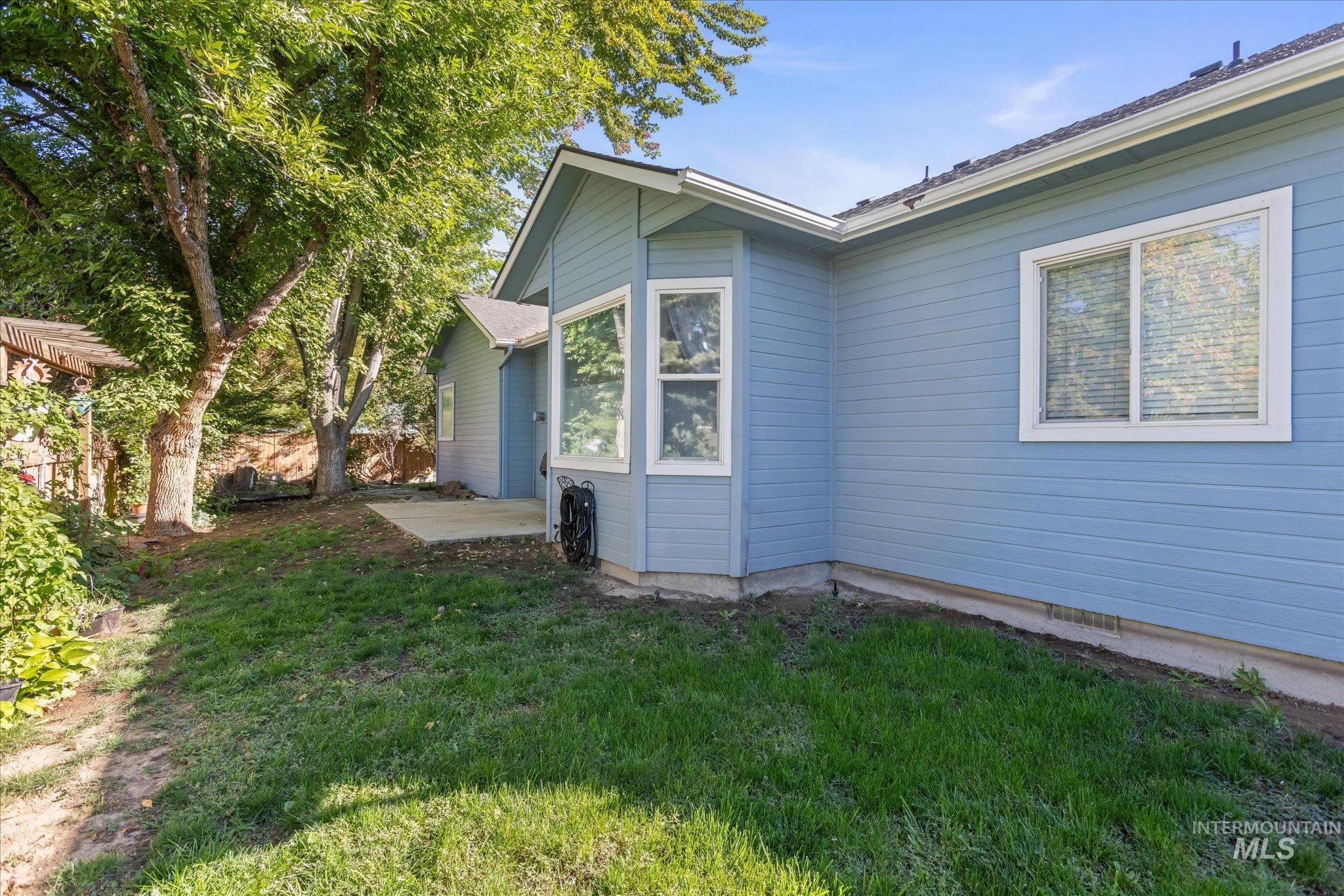 View of side of property featuring a patio and a lawn