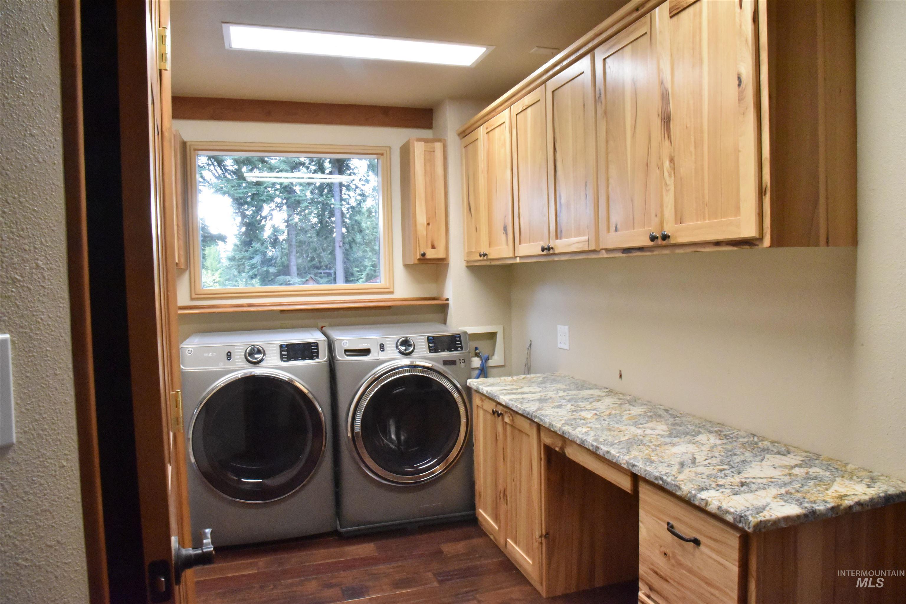 Washroom with dark wood finished floors, washing machine and dryer, and cabinet space