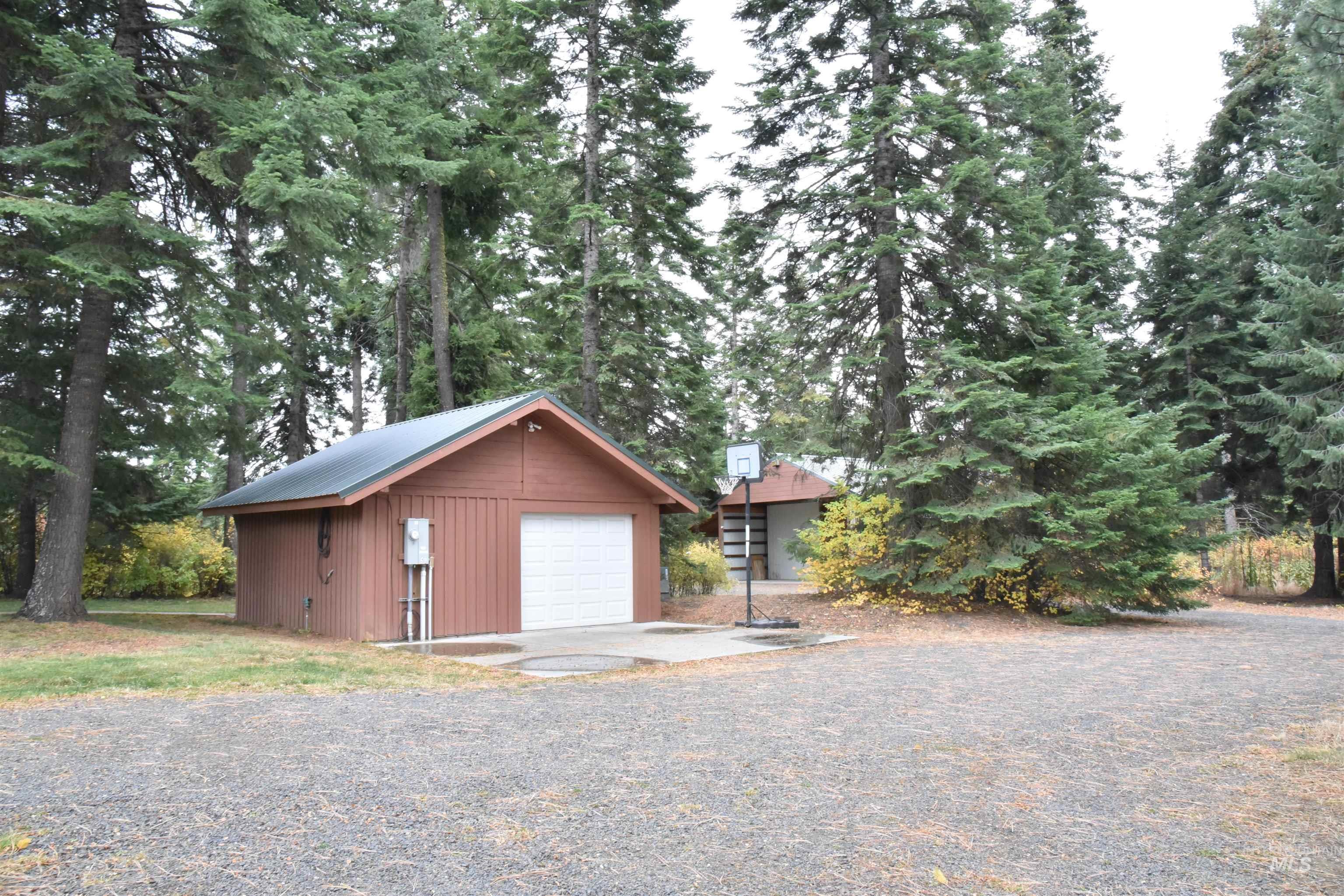 Detached garage with view of wooded area and driveway