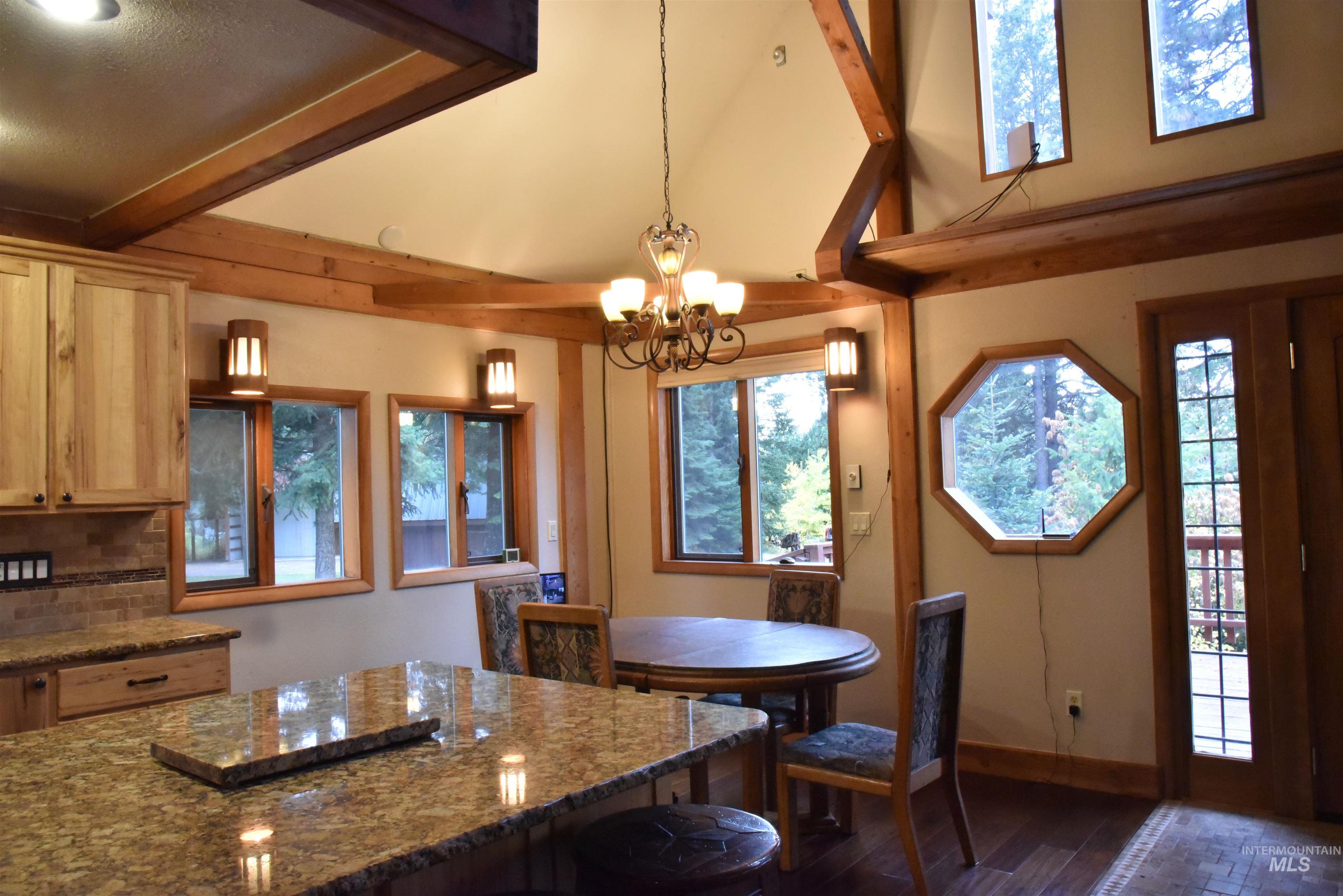 Kitchen featuring beam ceiling, decorative light fixtures, tasteful backsplash, dark wood-style flooring, and dark stone countertops