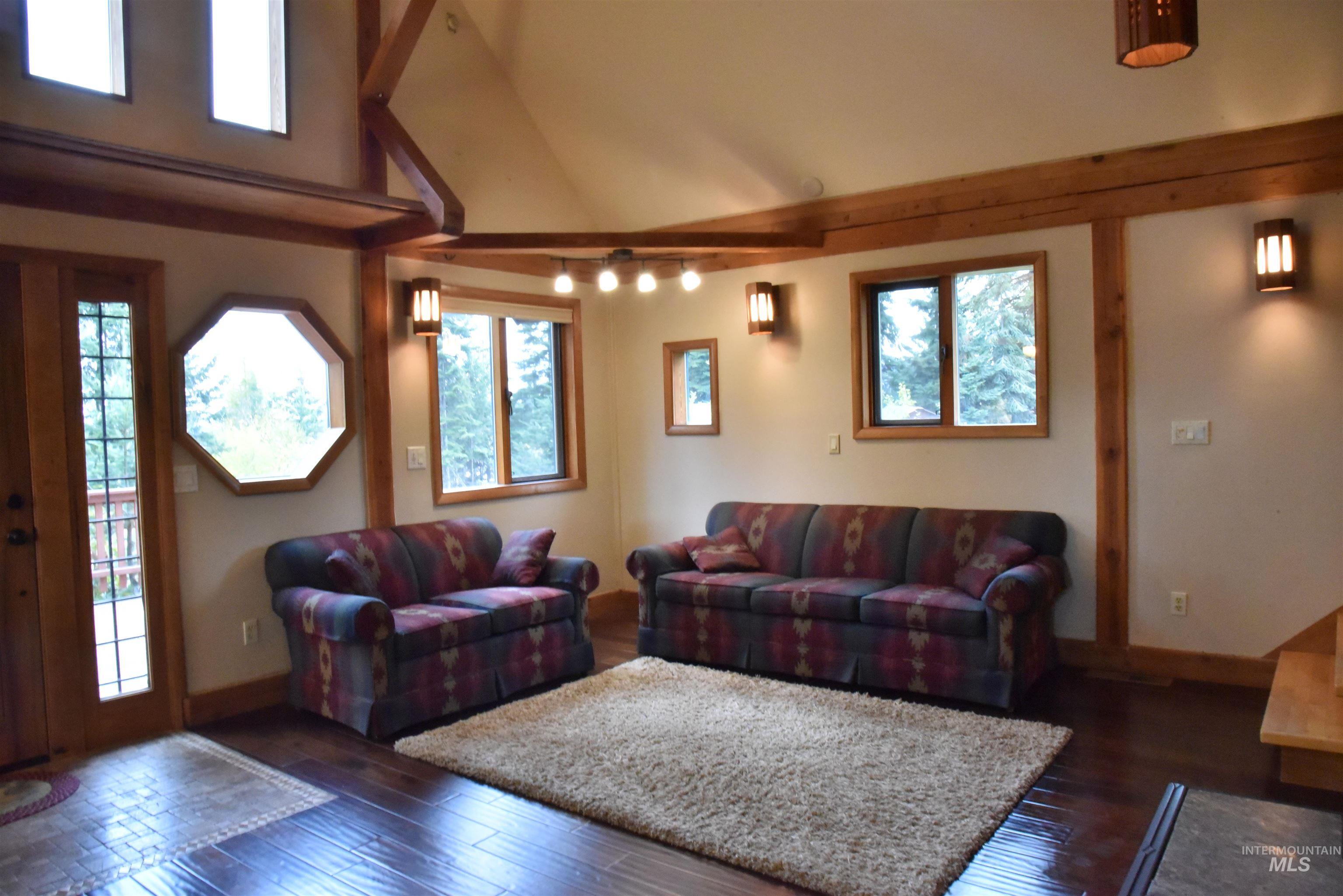 Living room featuring dark wood-type flooring and high vaulted ceiling