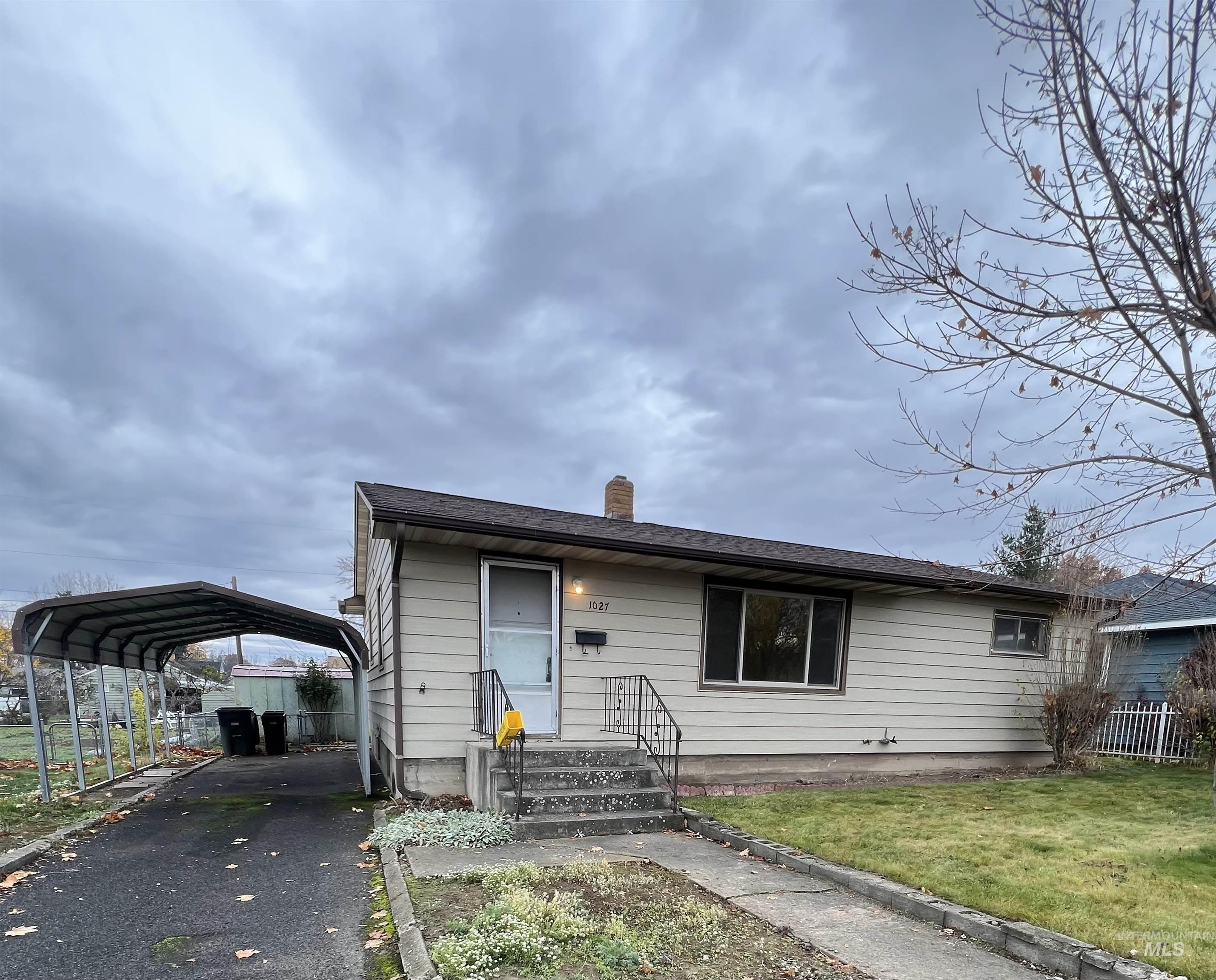 View of front of home featuring a chimney, a detached carport, and asphalt driveway