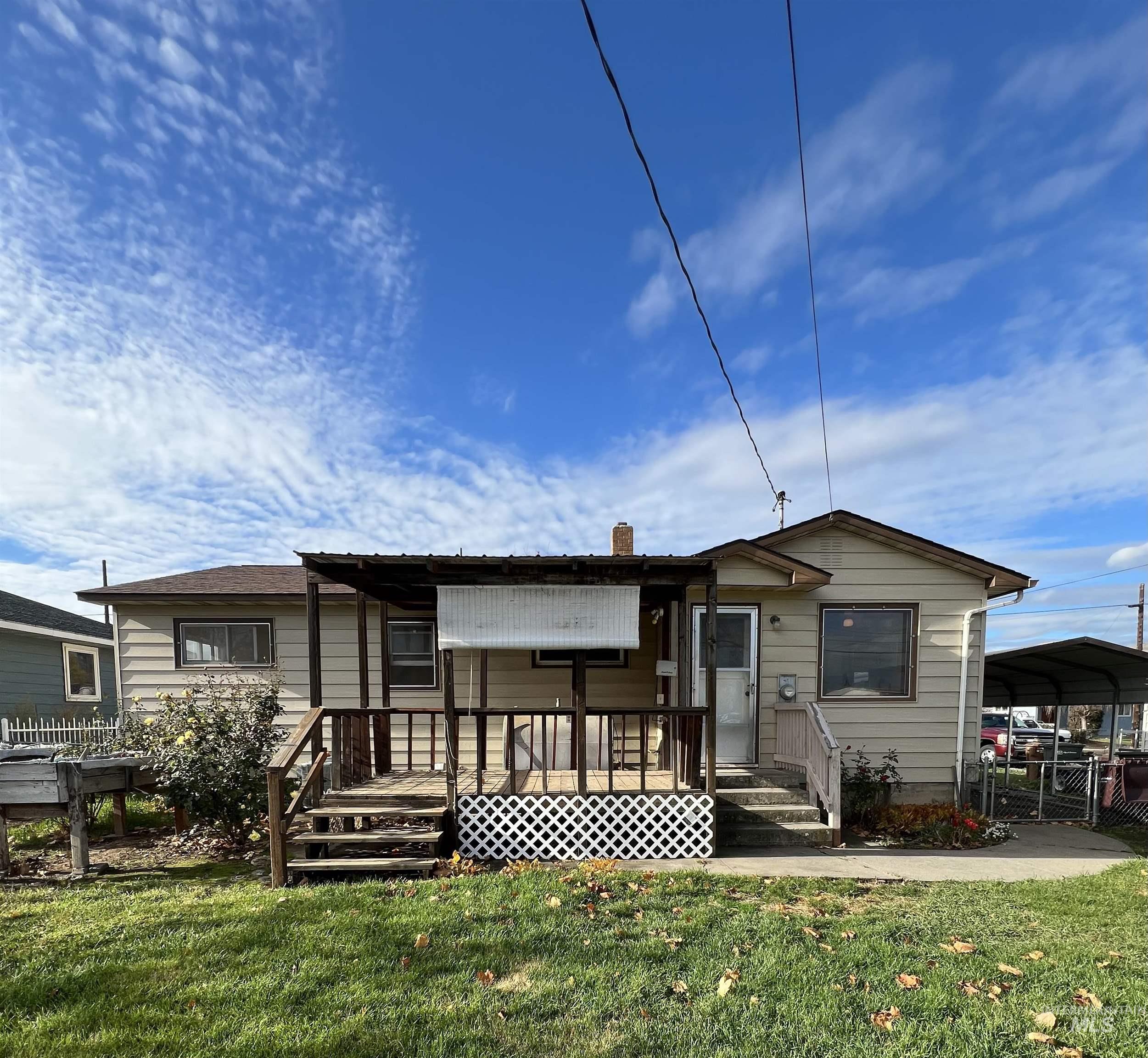 View of front facade featuring a front yard, a wooden deck, a carport, and a chimney