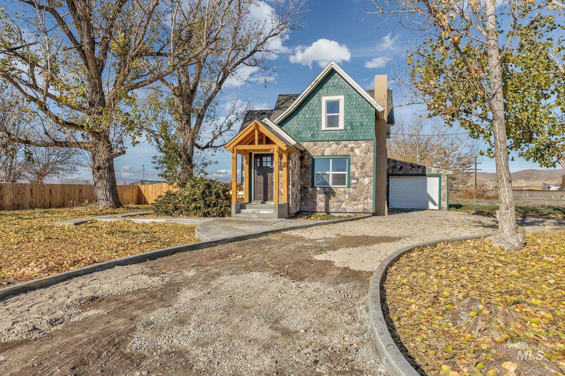 View of front of home with stone siding, a chimney, a garage, and driveway