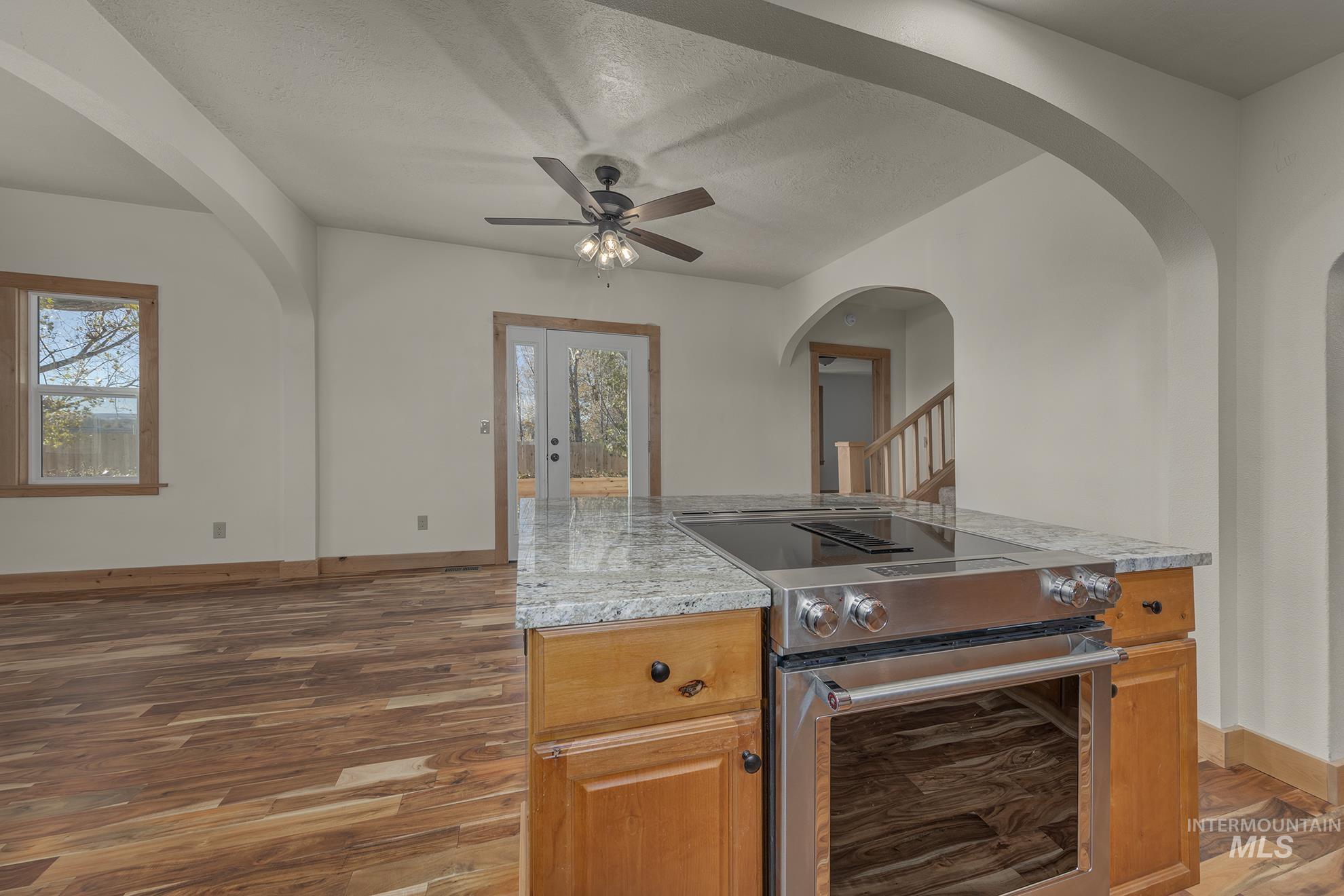 Kitchen with stainless steel electric range oven, arched walkways, a center island, dark wood-style flooring, and plenty of natural light