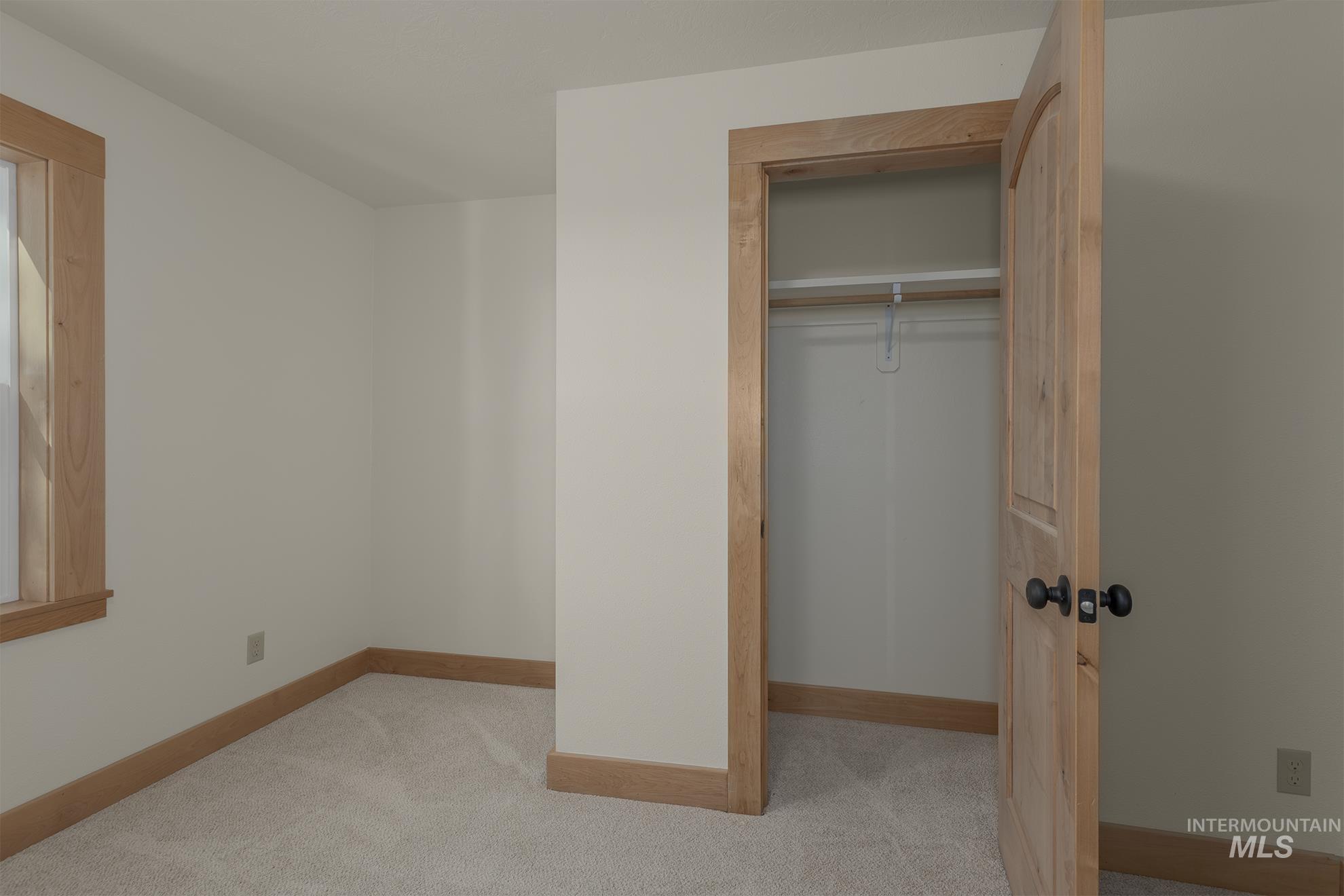 Unfurnished bedroom with light carpet and a closet