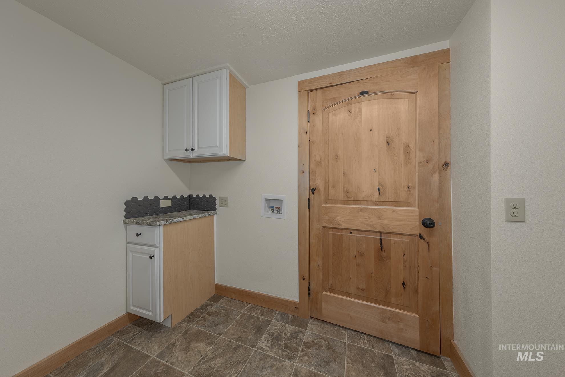 Laundry area featuring hookup for a washing machine, cabinet space, and a textured ceiling