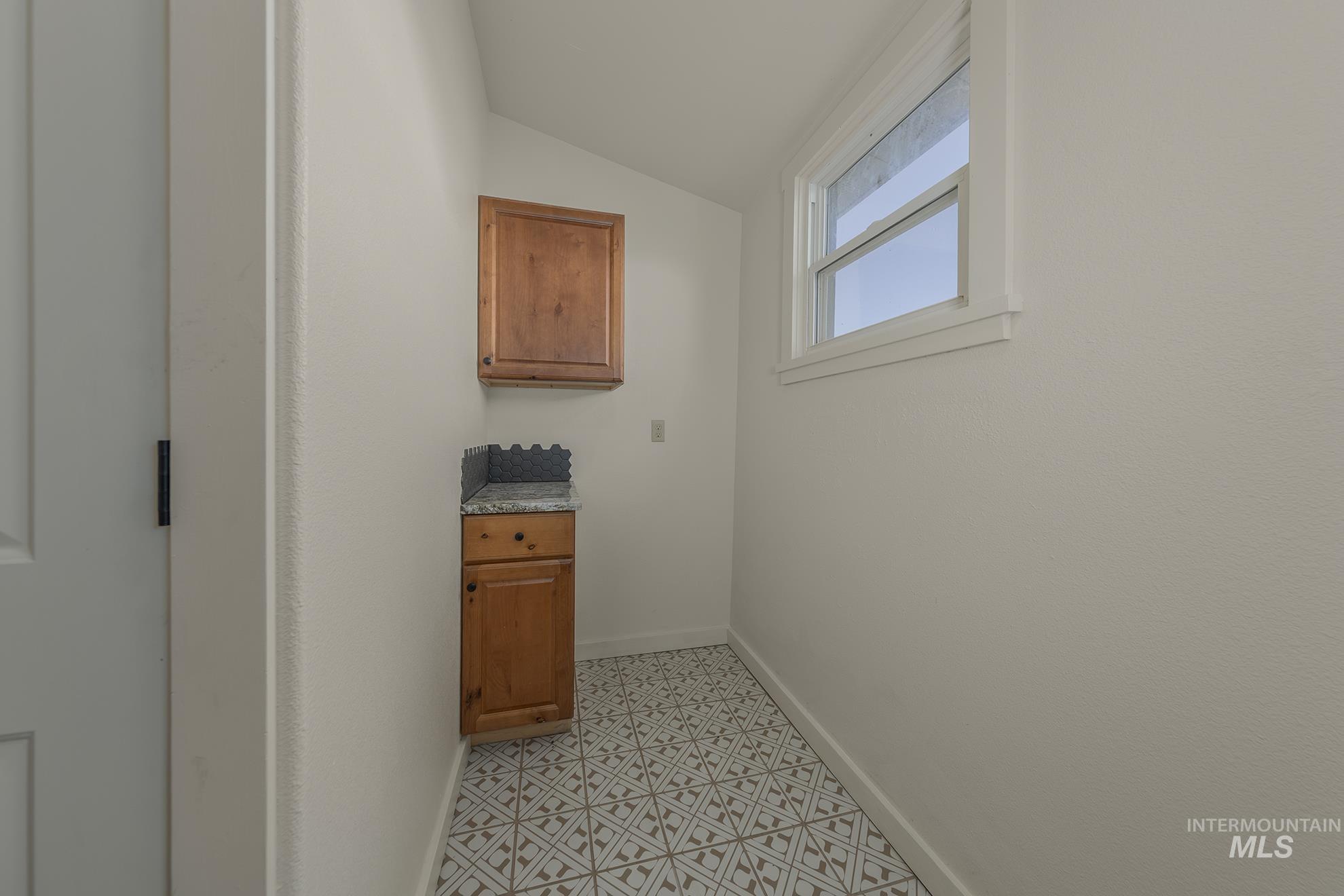 Laundry area with vaulted ceiling and baseboards