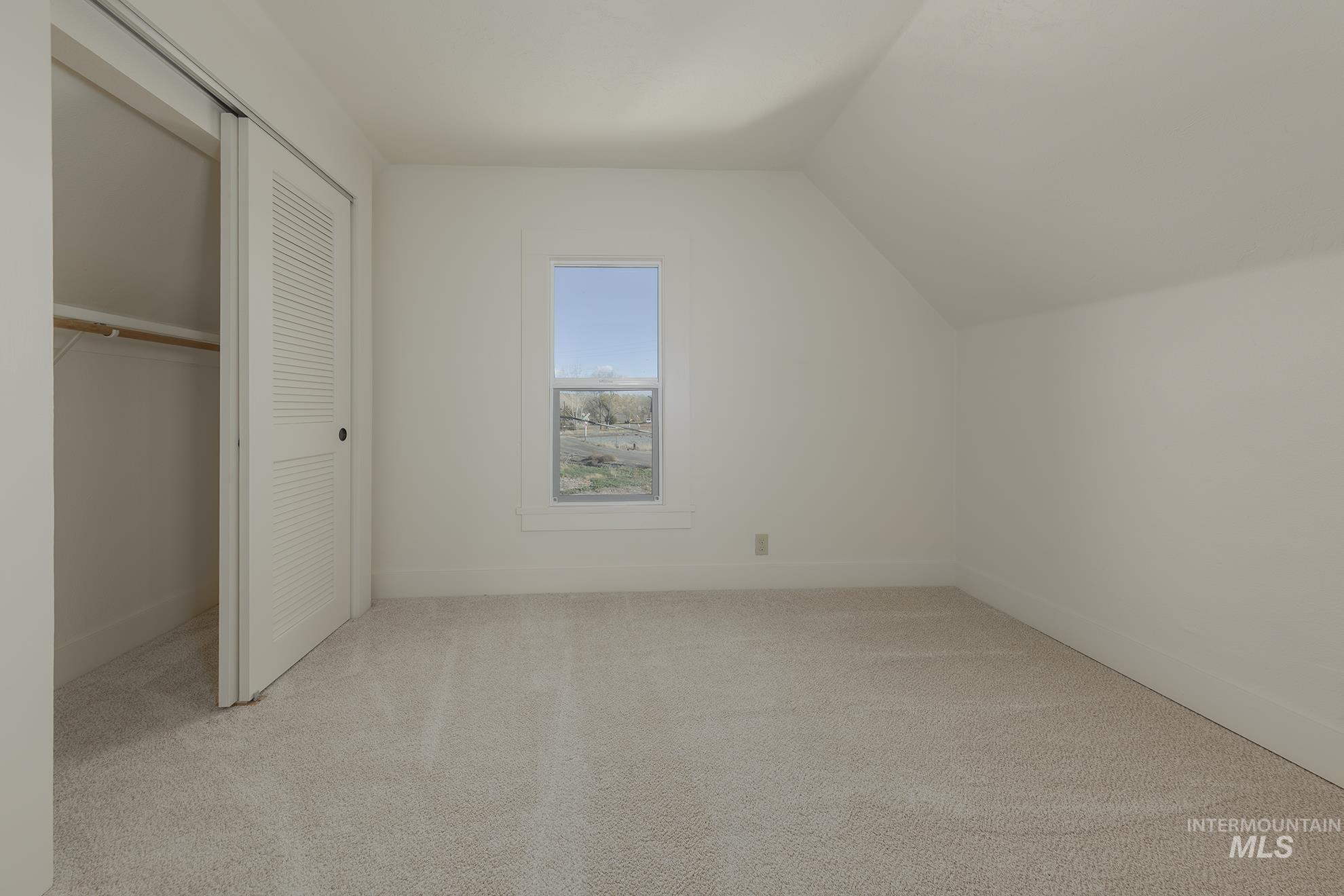Additional living space with light colored carpet and lofted ceiling