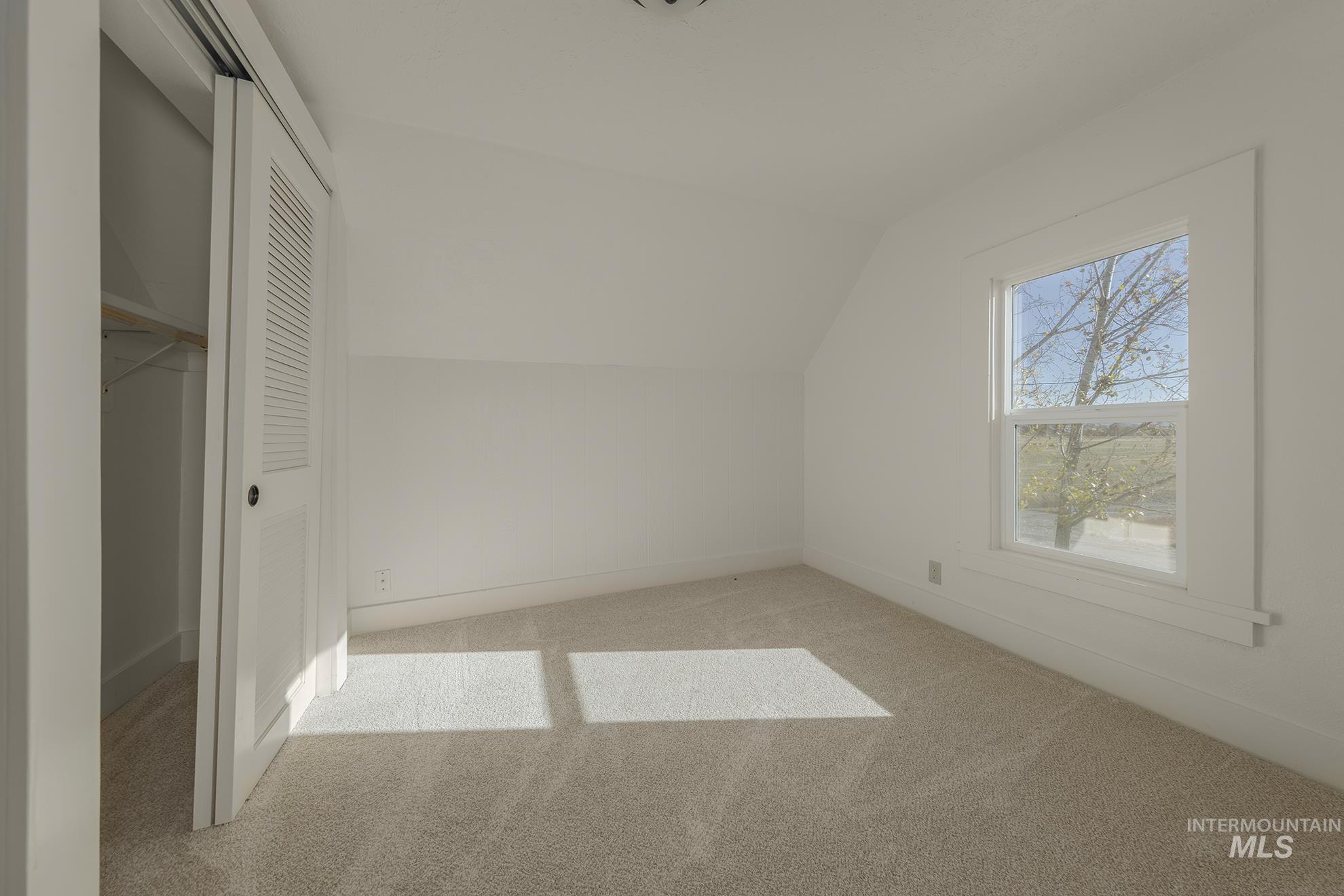 Additional living space featuring lofted ceiling and carpet floors