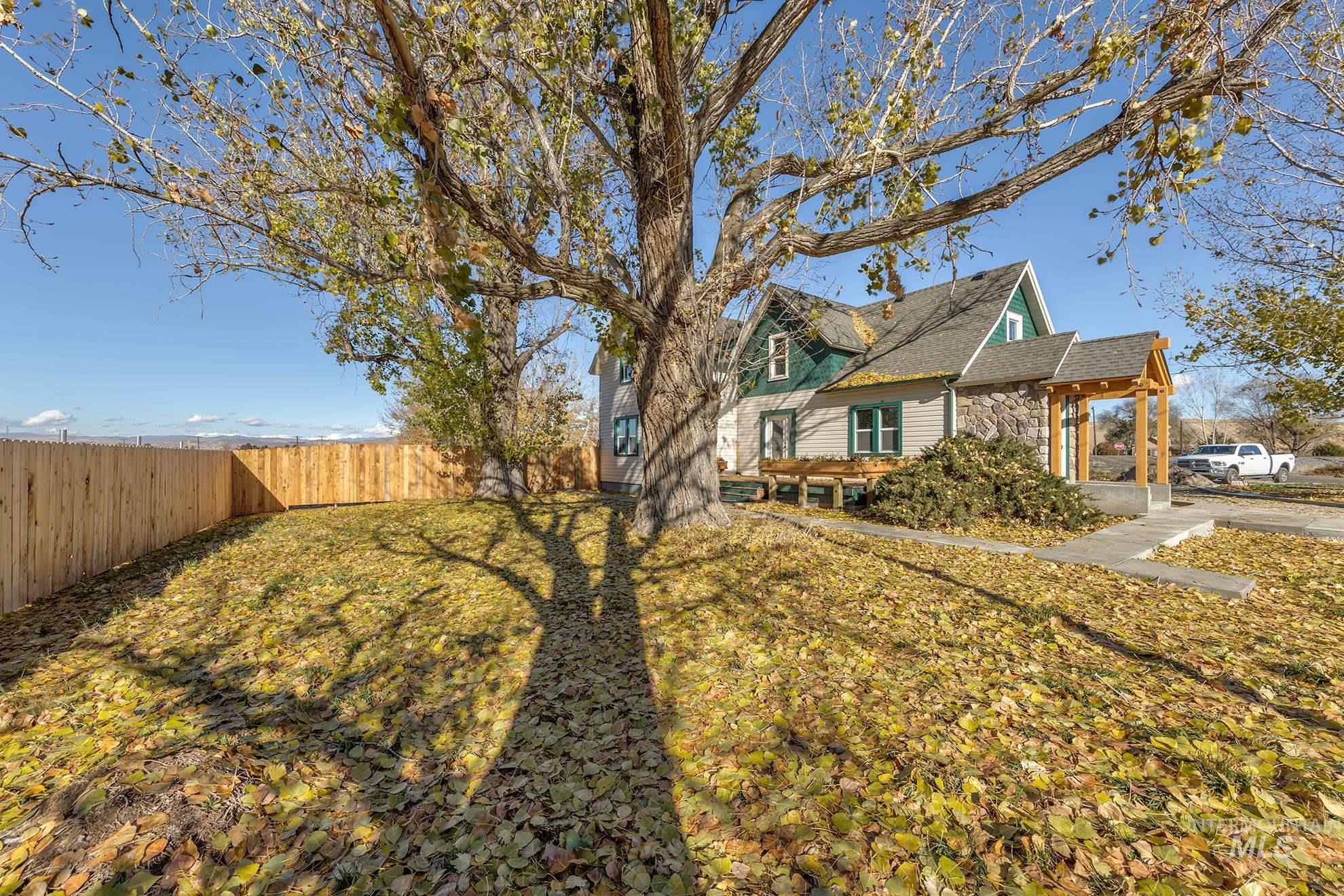 View of side of home featuring stone siding, a fenced backyard, and roof with shingles