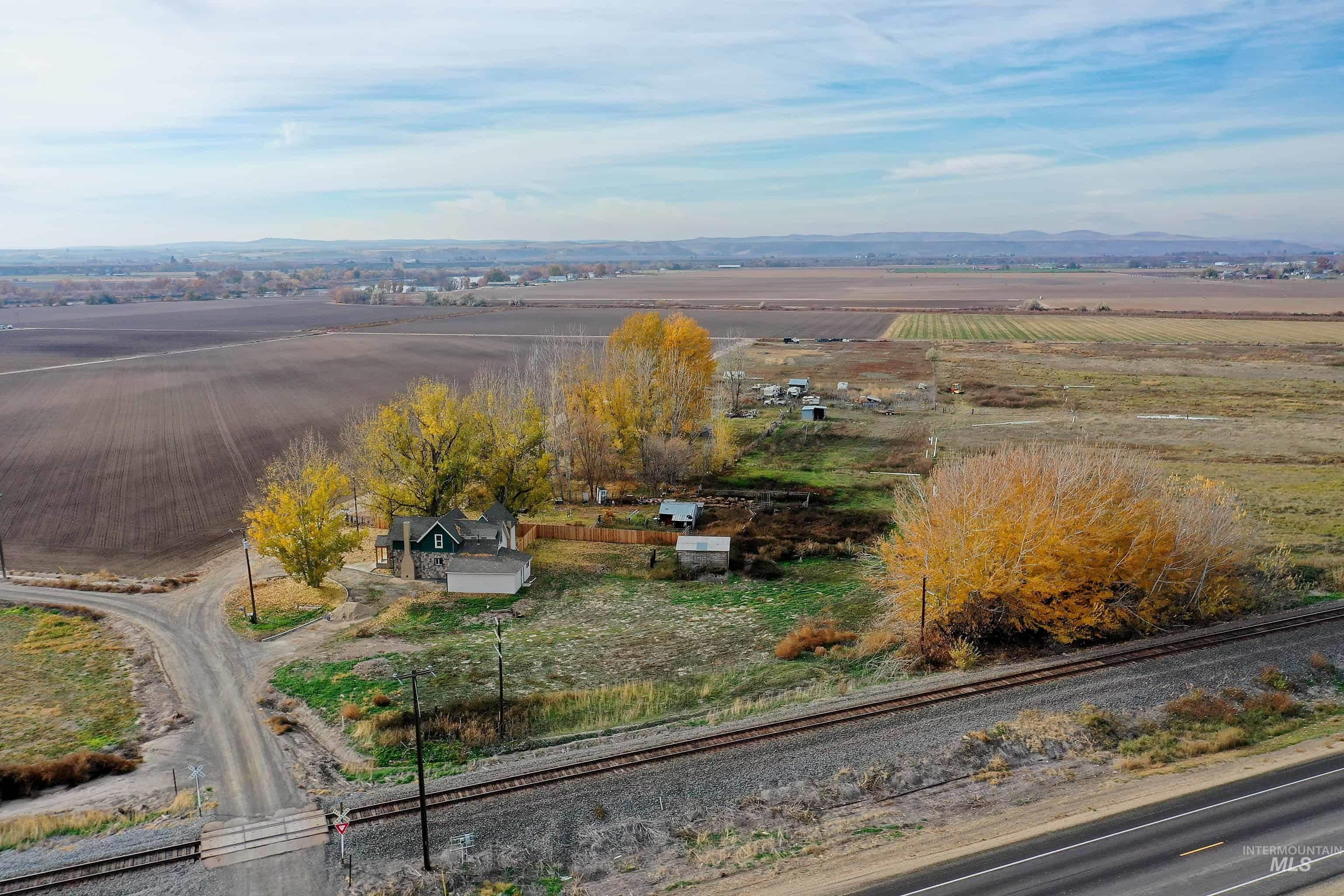 Aerial view of sparsely populated area featuring a mountain backdrop and large plots for crops