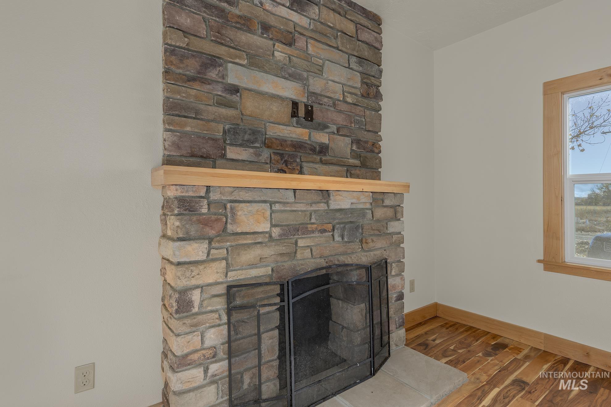 Detailed view of wood finished floors and a stone fireplace