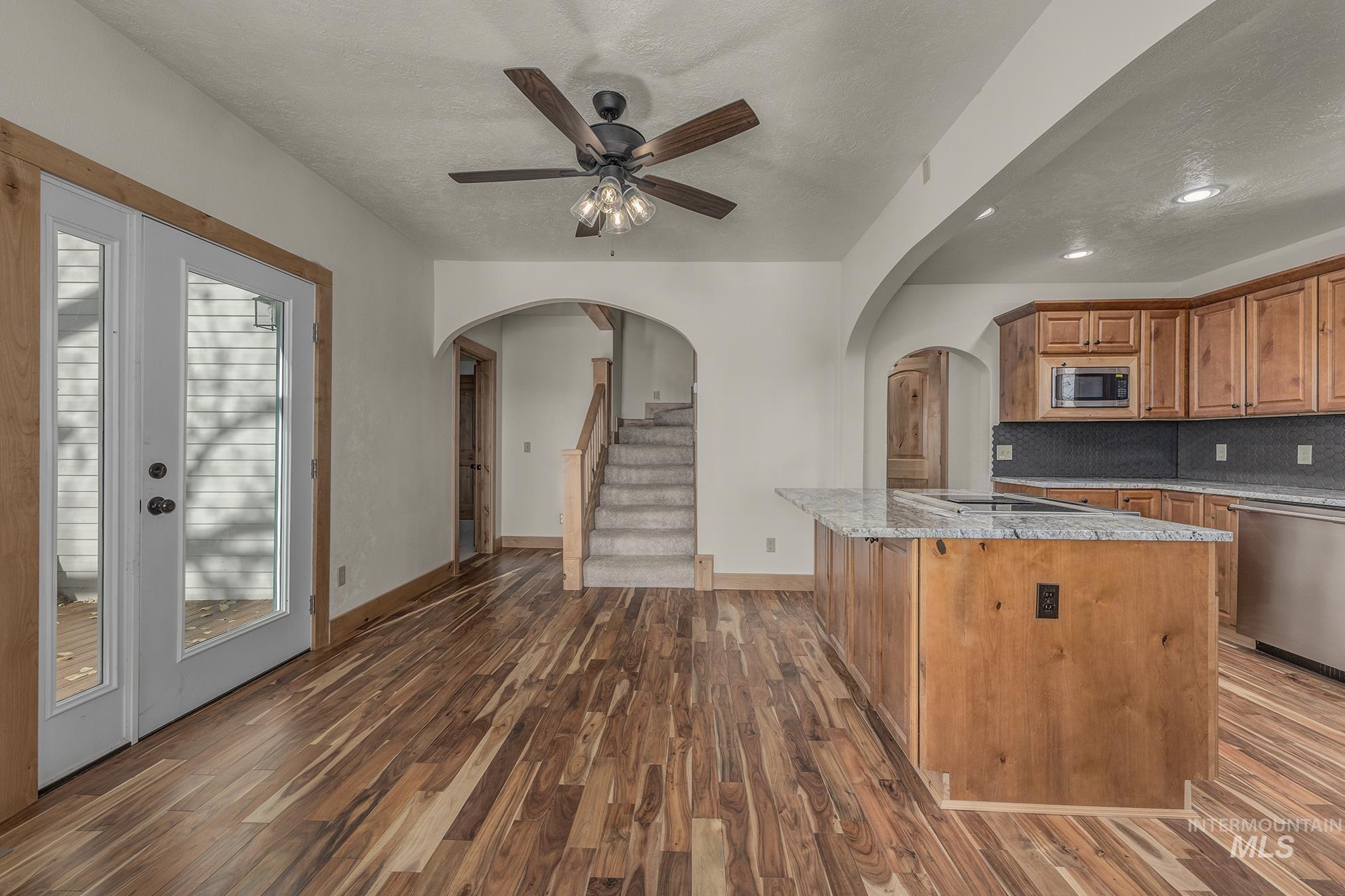 Kitchen featuring light stone counters, tasteful backsplash, brown cabinets, a center island, and dark wood-style floors
