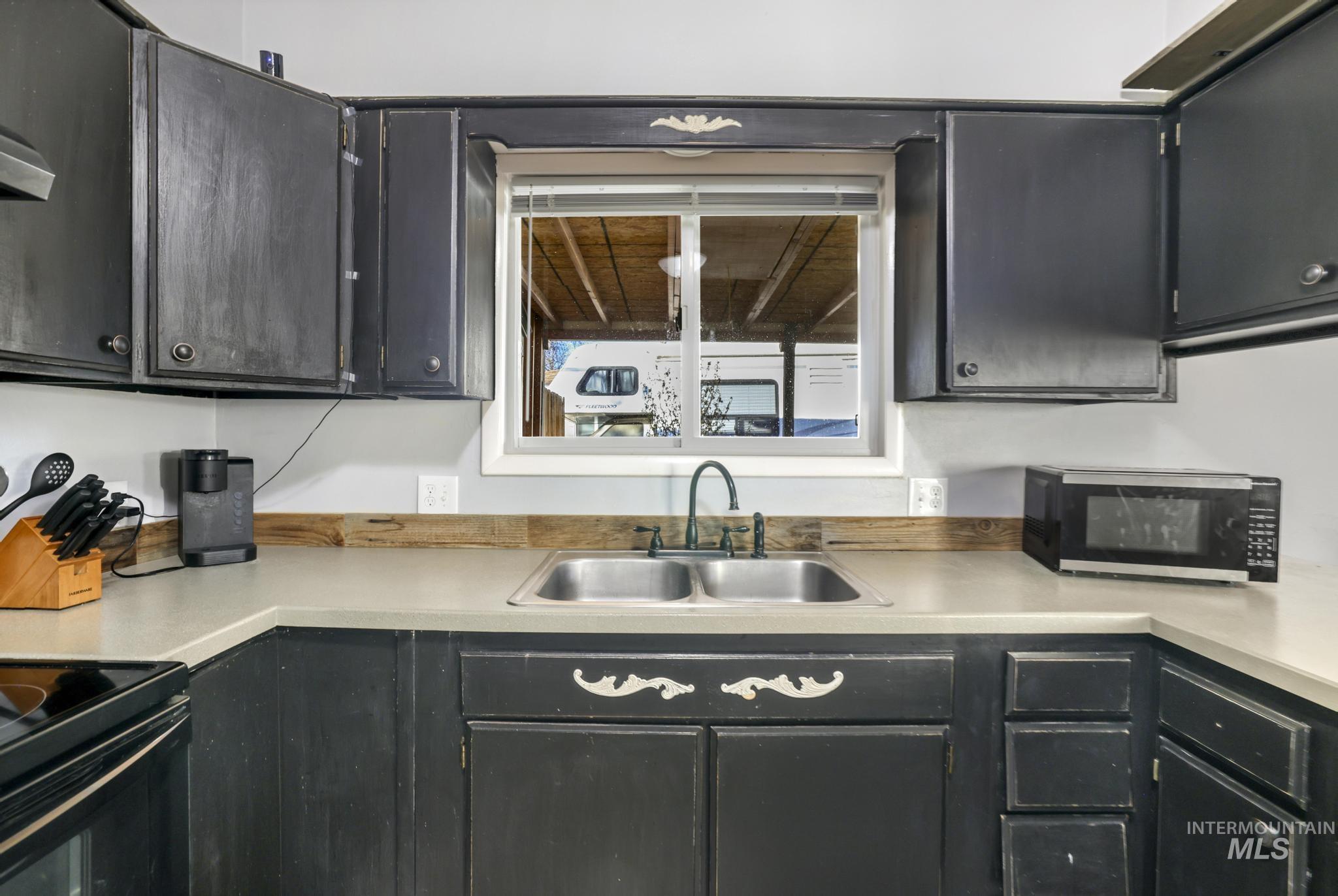Kitchen featuring light countertops, electric range, and dark cabinetry