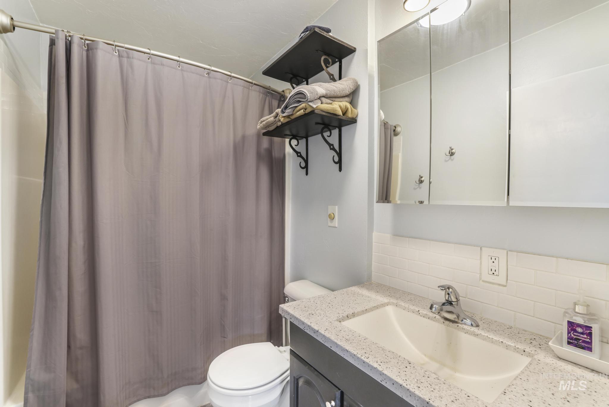 Full bath with vanity, backsplash, and shower / bathtub combination with curtain