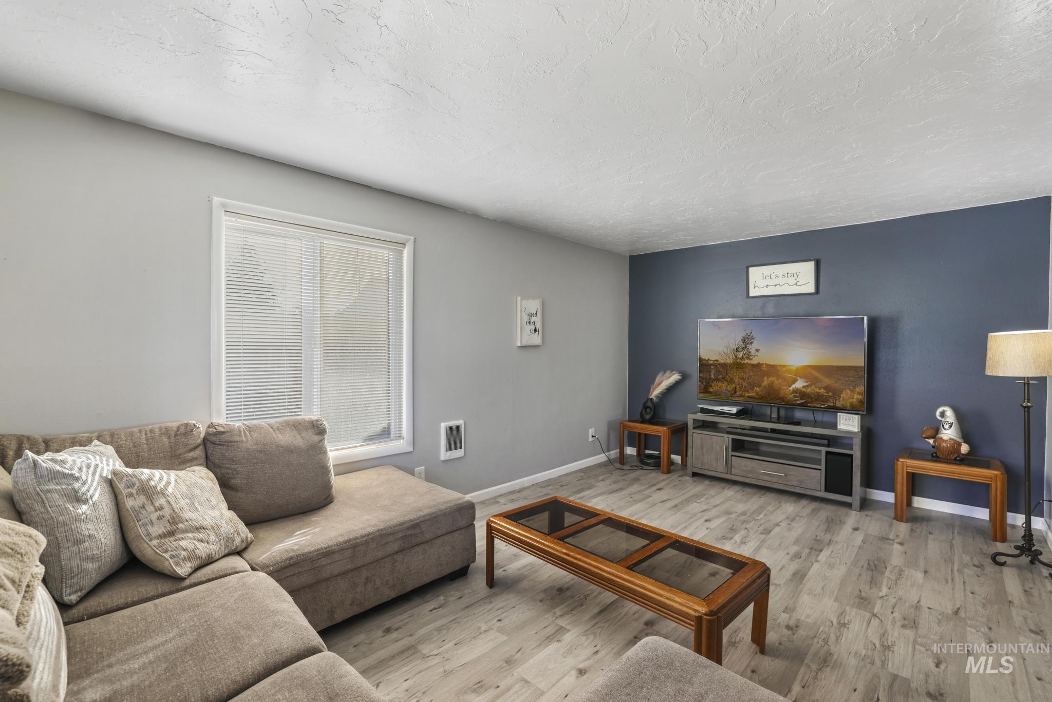 Living room featuring a textured ceiling, light wood-style floors, and heating unit