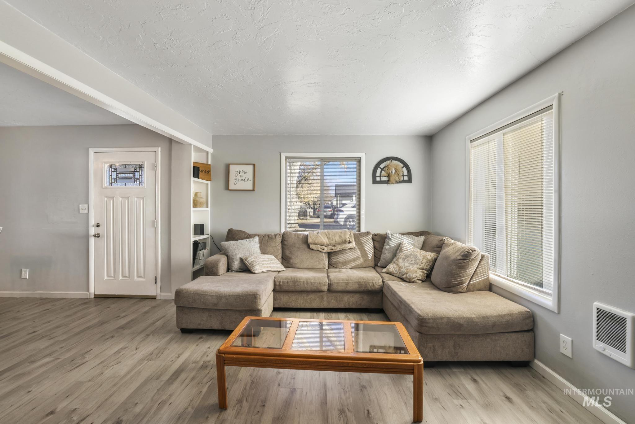 Living area with wood finished floors, heating unit, and a textured ceiling