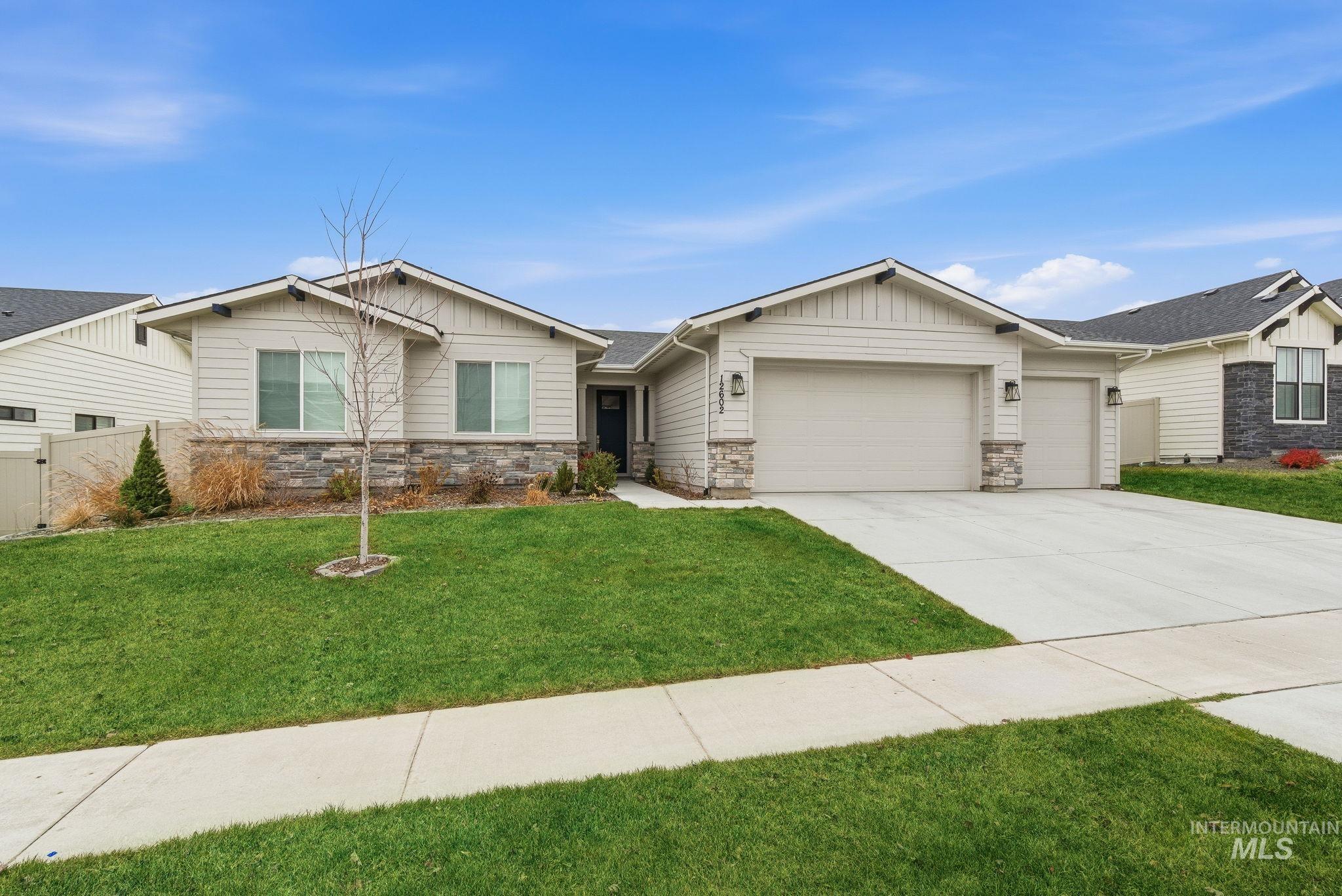 Craftsman inspired home with stone siding, driveway, board and batten siding, and an attached garage