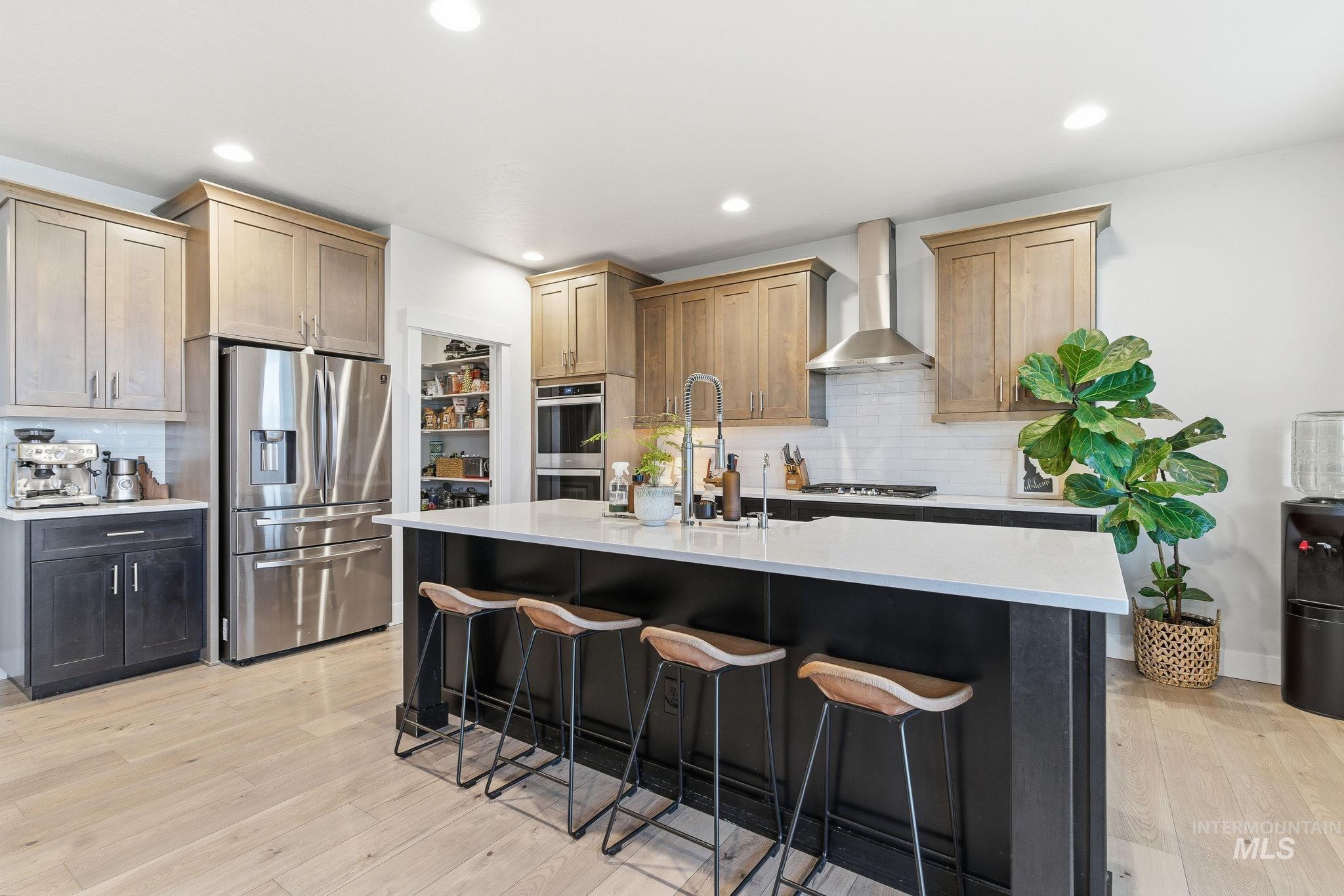 Kitchen featuring tasteful backsplash, appliances with stainless steel finishes, recessed lighting, a kitchen bar, and light wood-style flooring
