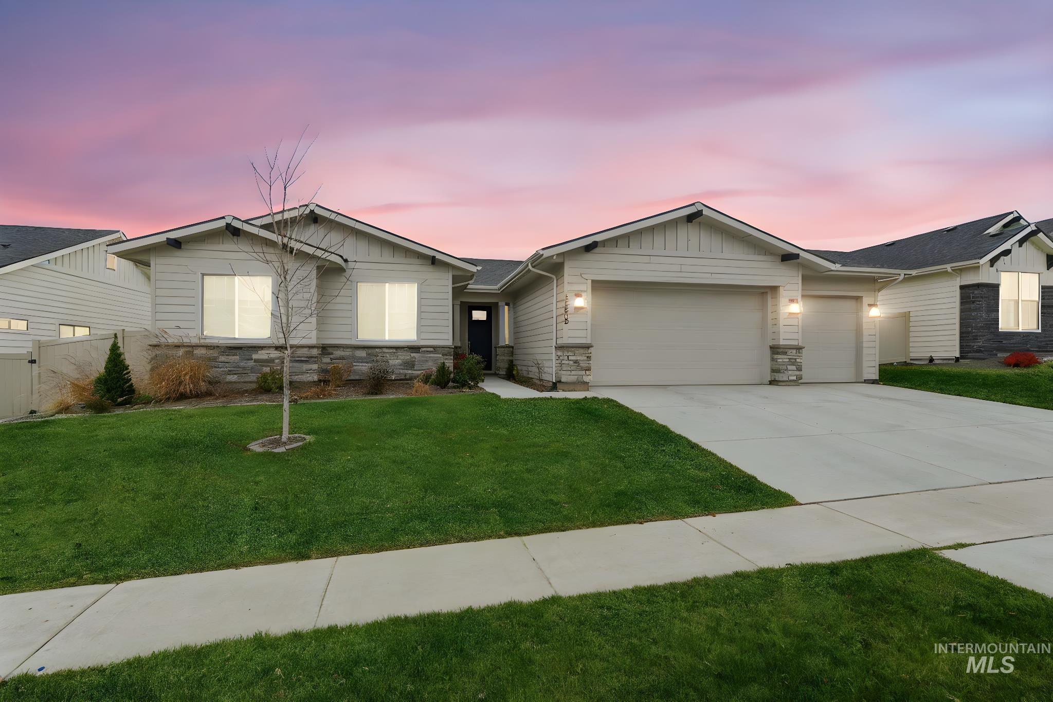 View of front of home with stone siding, a front yard, and board and batten siding