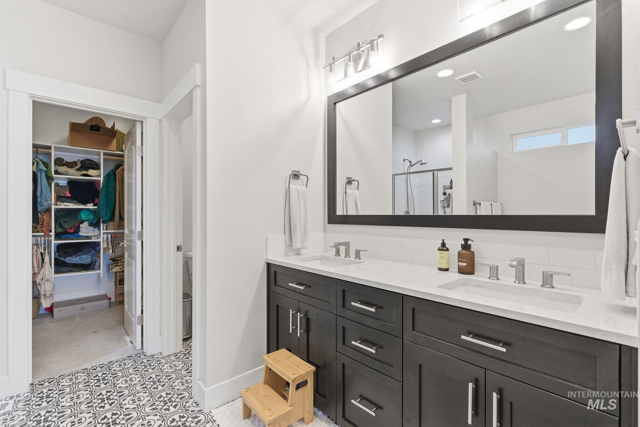 Full bathroom featuring double vanity, a walk in closet, a stall shower, and recessed lighting