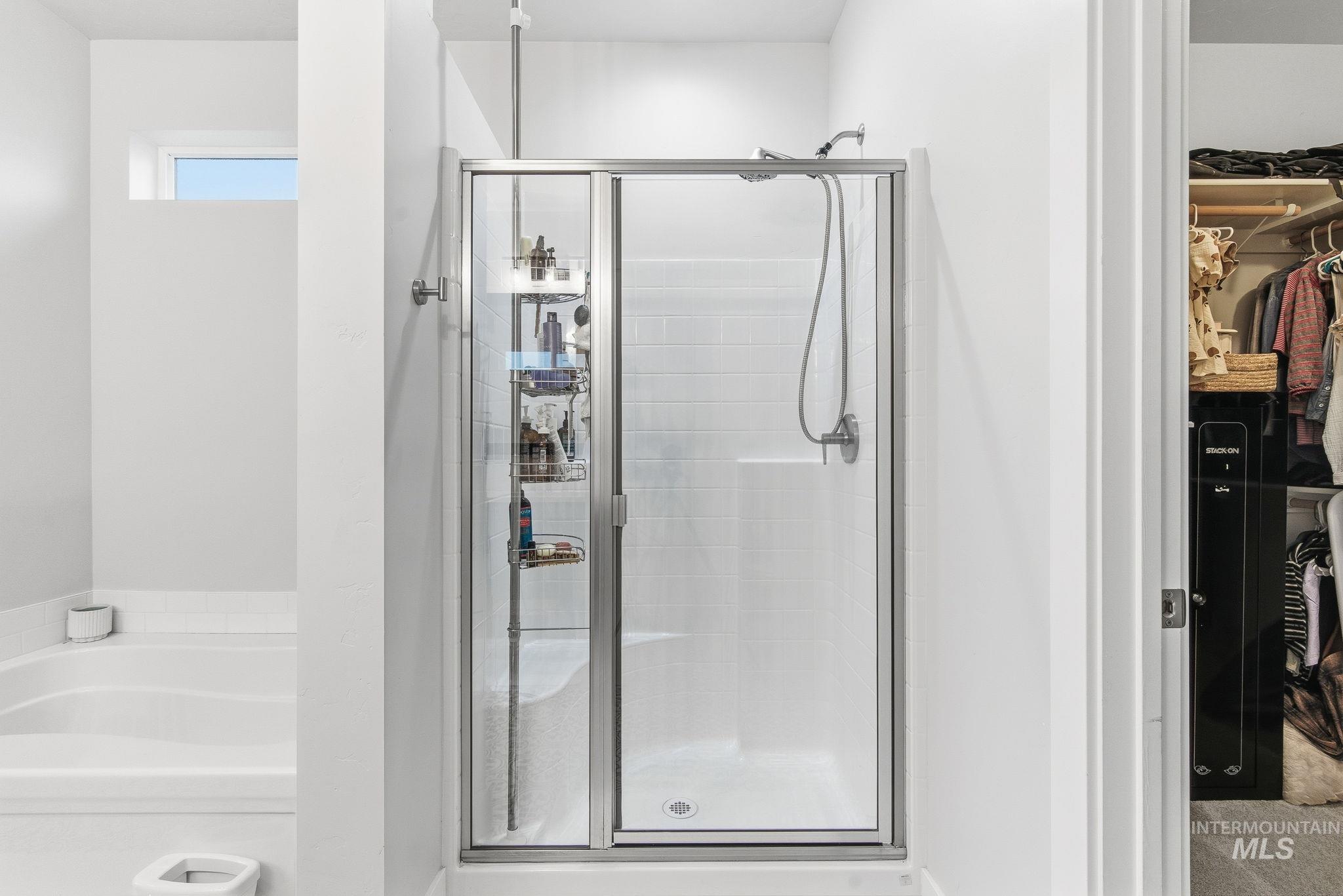 Bathroom featuring a spacious closet, a garden tub, and a shower stall