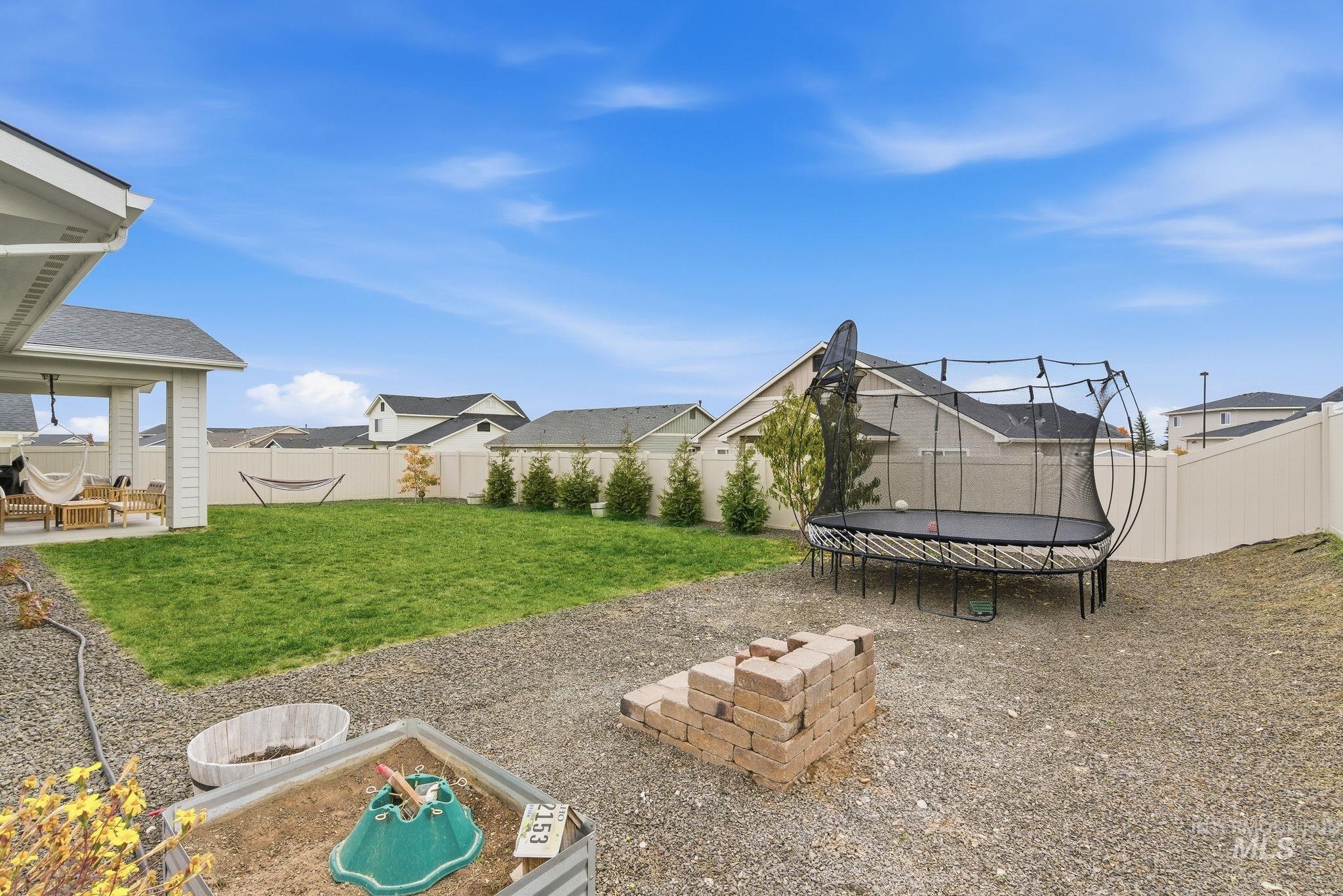 Fenced backyard featuring a trampoline and a patio area