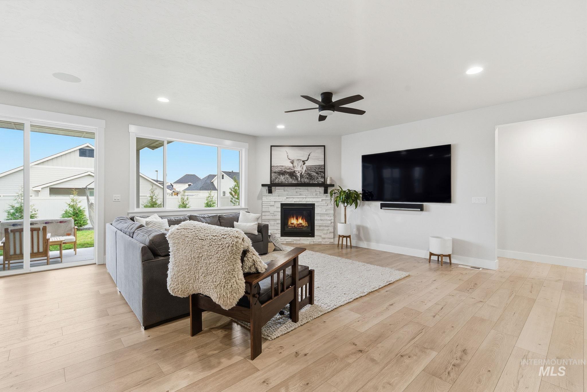 Living room featuring light wood-style floors, a fireplace, recessed lighting, and ceiling fan