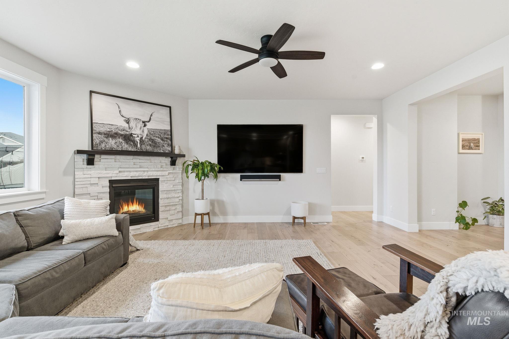 Living area featuring a fireplace, wood finished floors, a ceiling fan, and recessed lighting