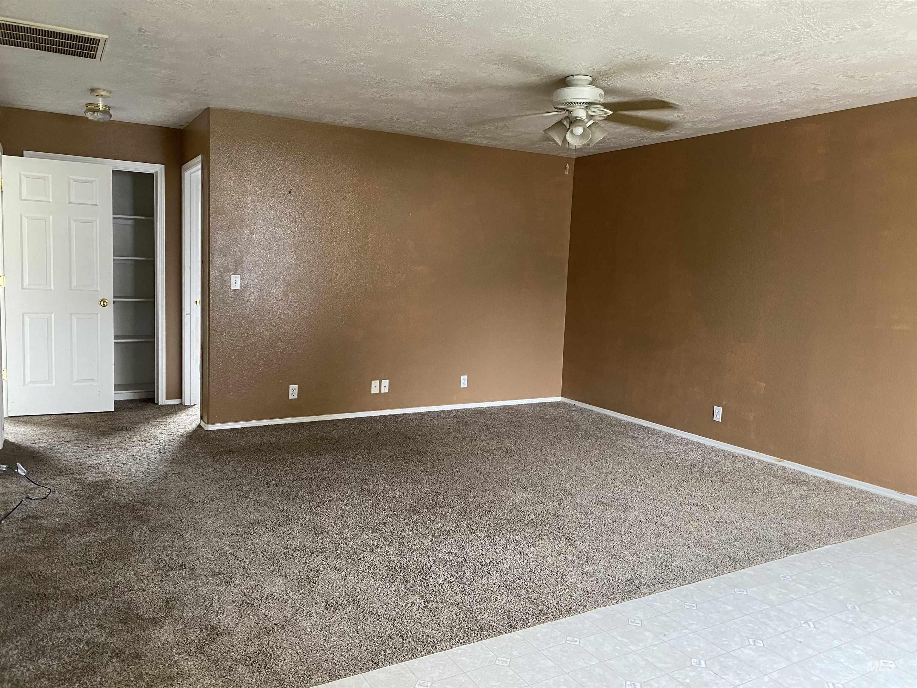 Carpeted empty room featuring a textured ceiling and a ceiling fan