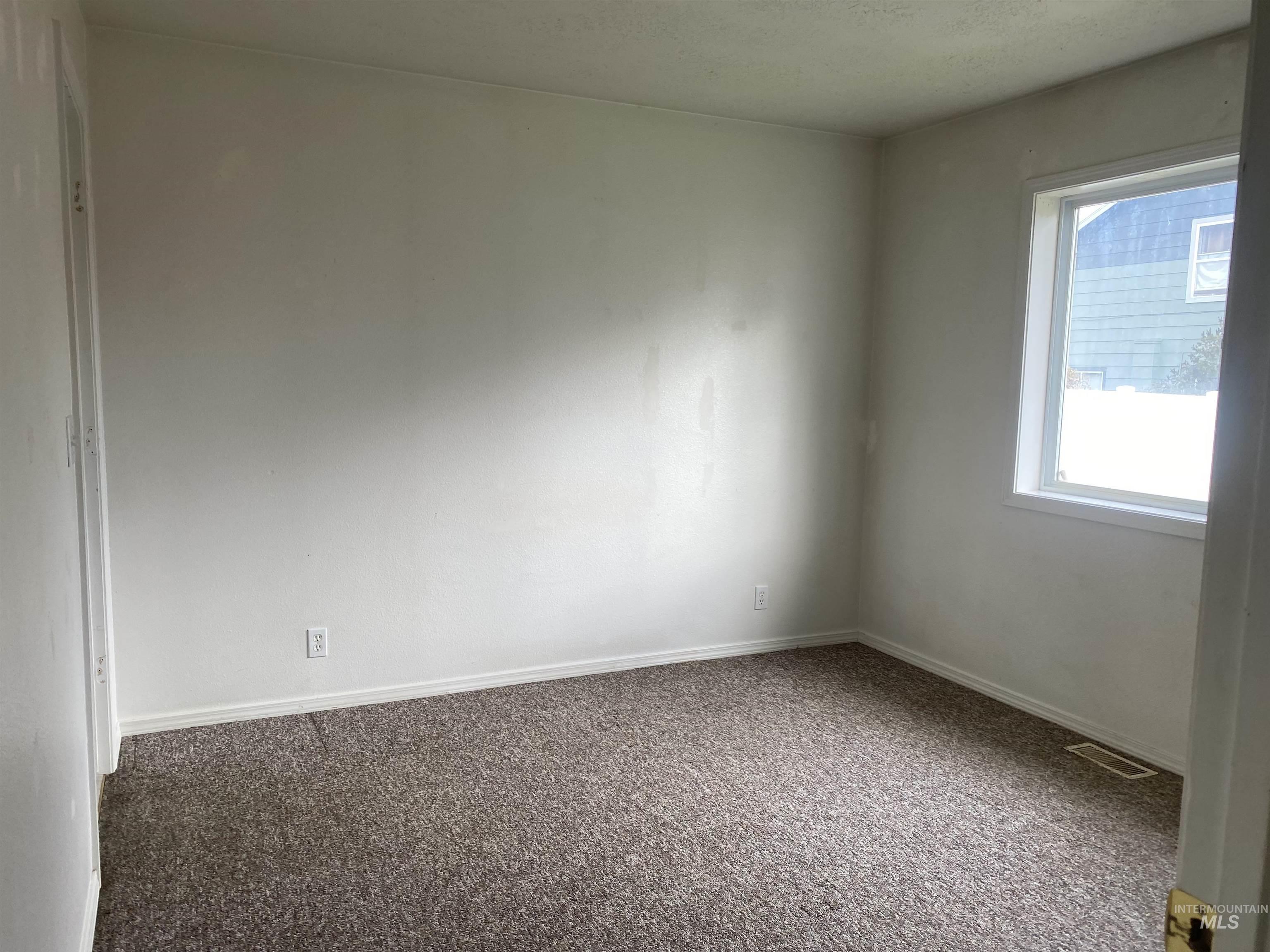 Carpeted empty room featuring baseboards
