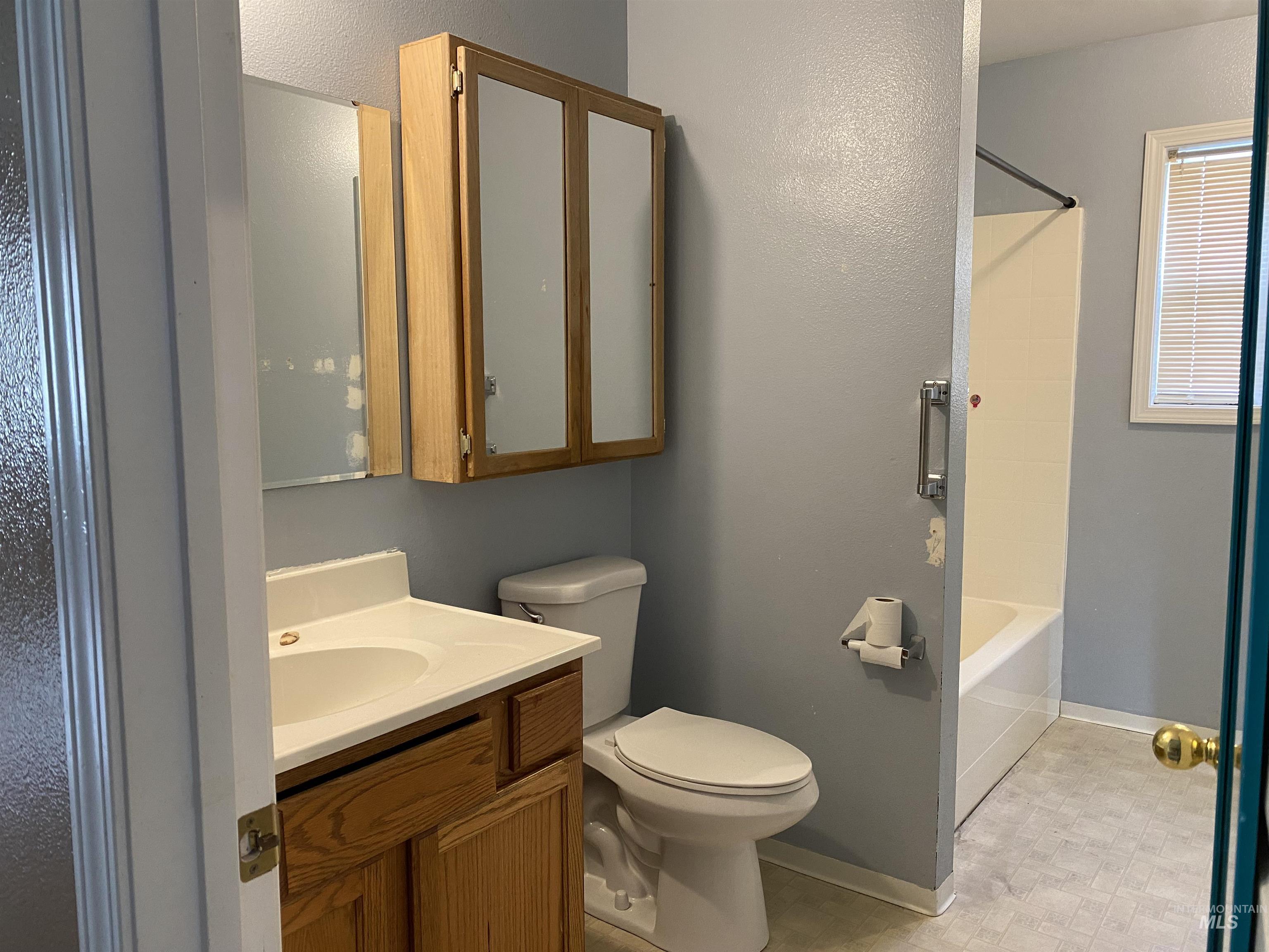 Full bathroom with vanity, shower / bath combination, and a textured wall