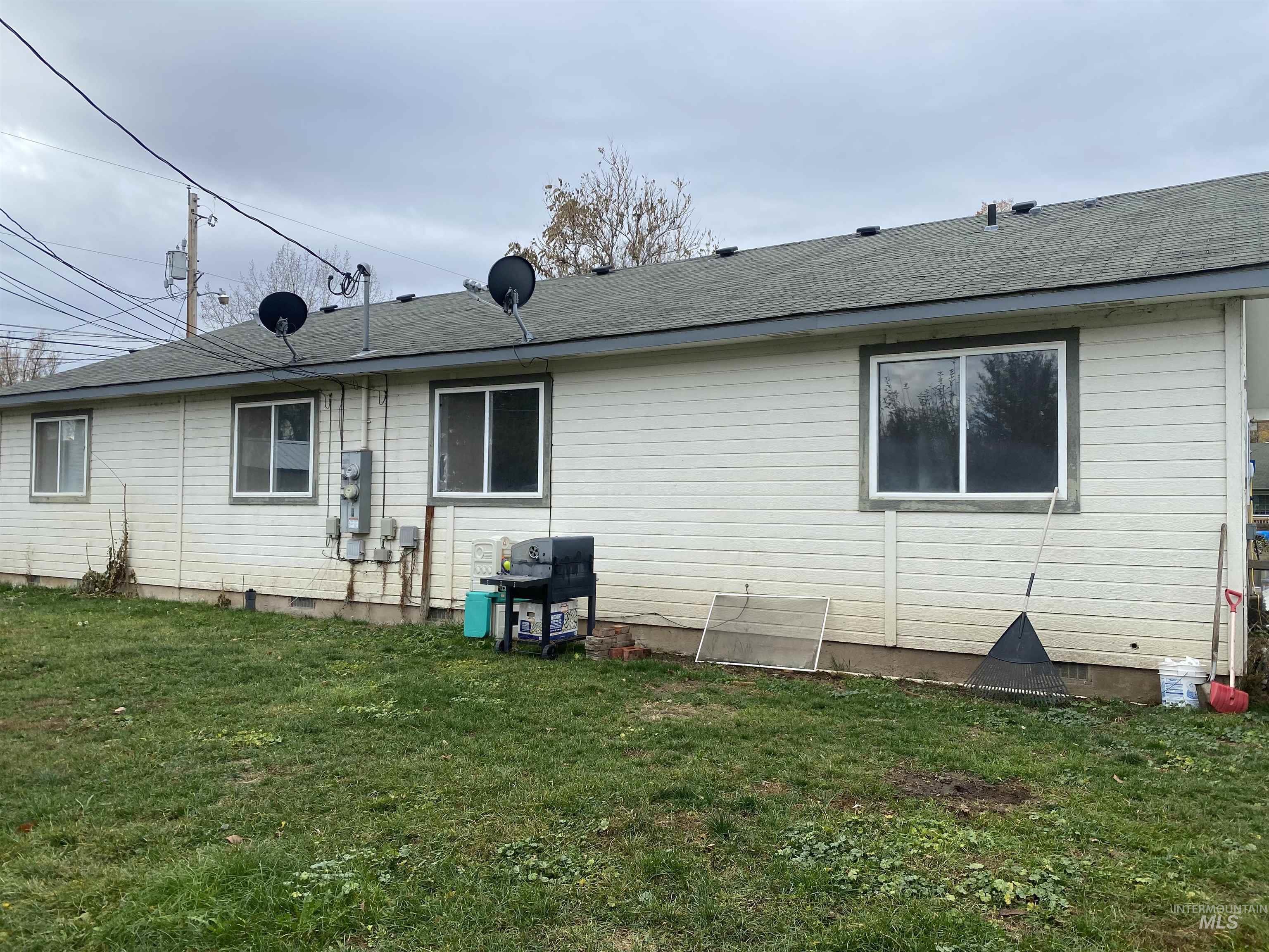 Rear view of property with a yard, crawl space, and roof with shingles