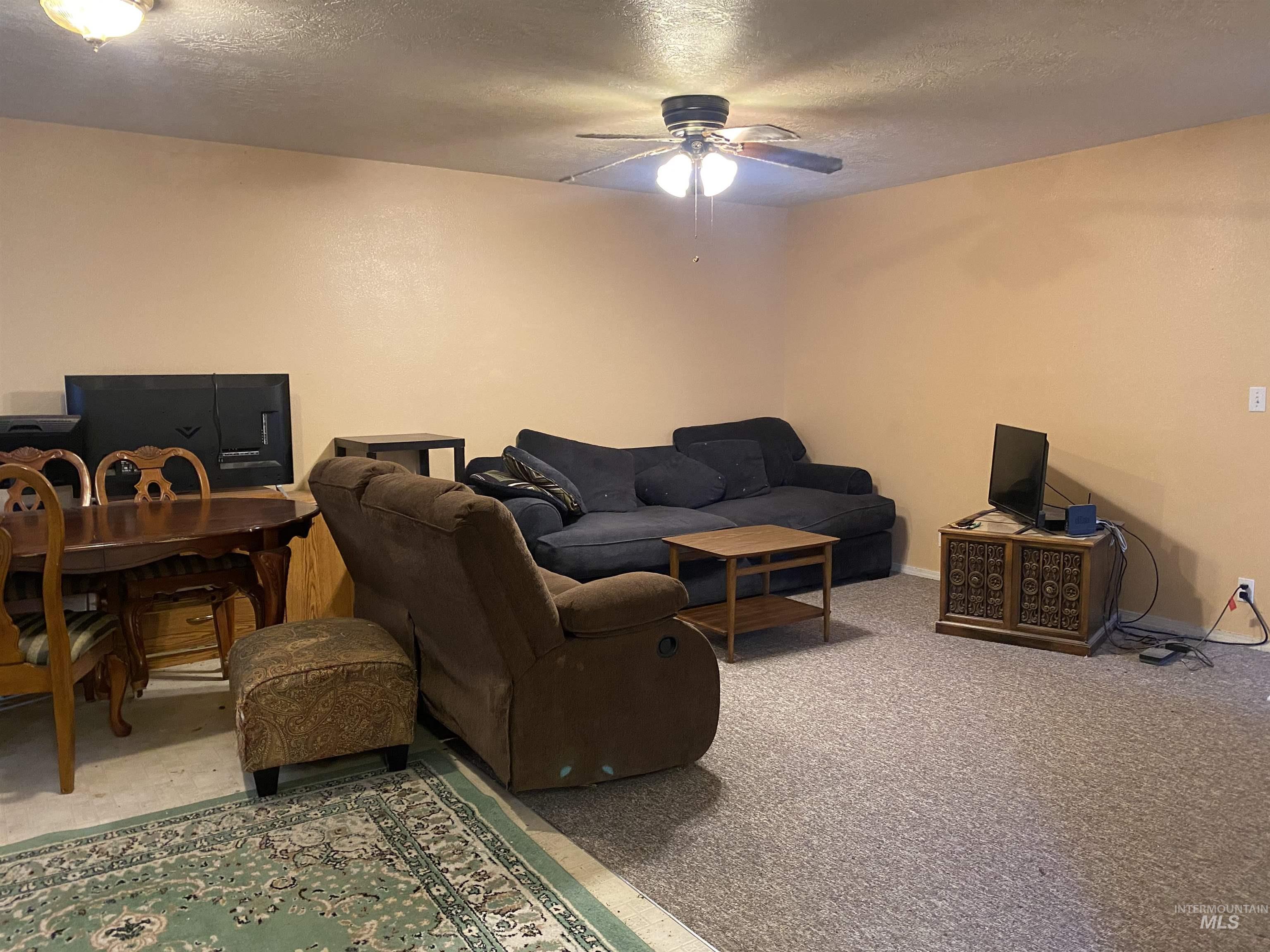 Living room featuring a textured ceiling, carpet, an office area, and ceiling fan