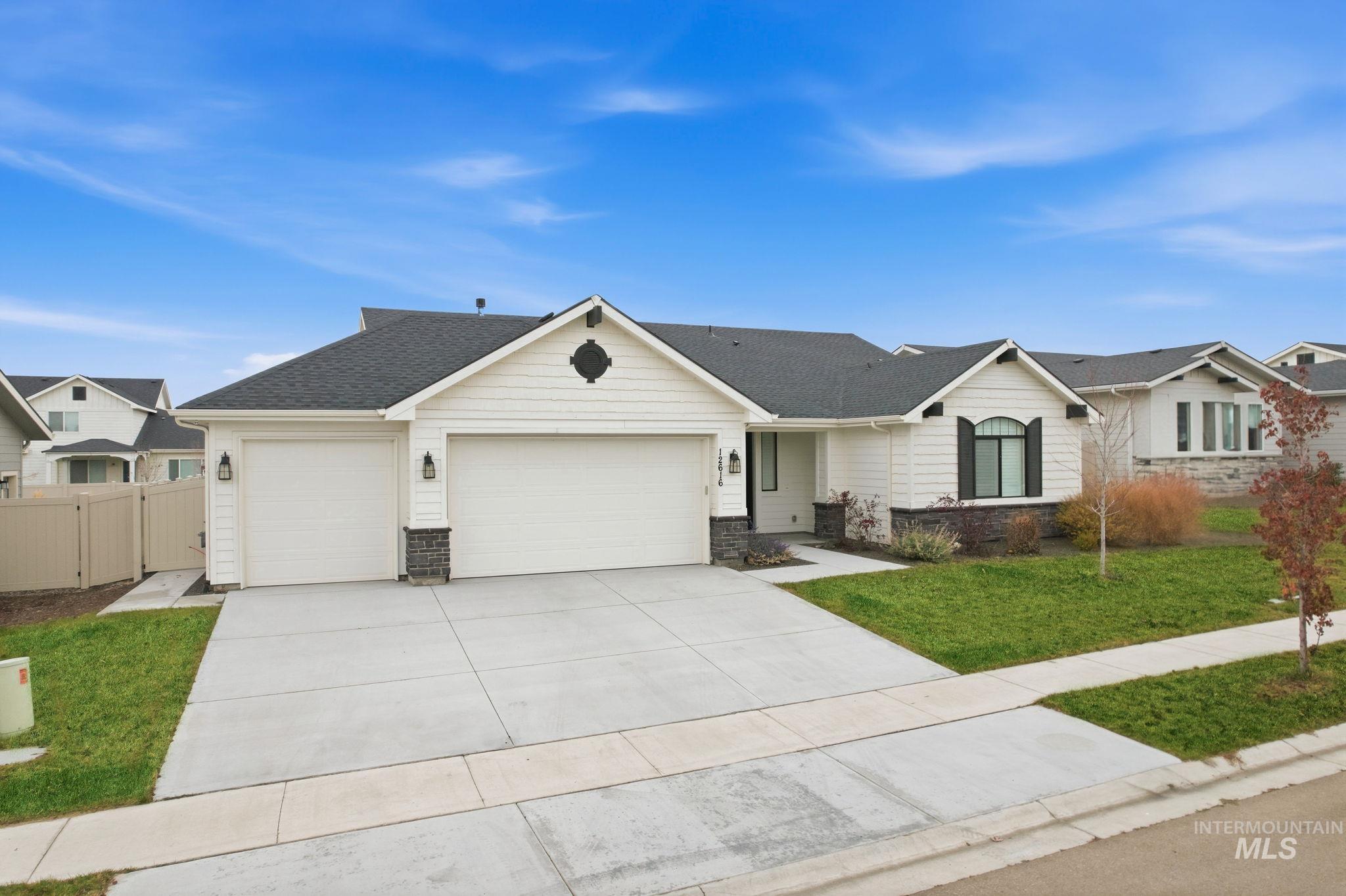 Ranch-style home featuring stone siding, a garage, roof with shingles, and driveway