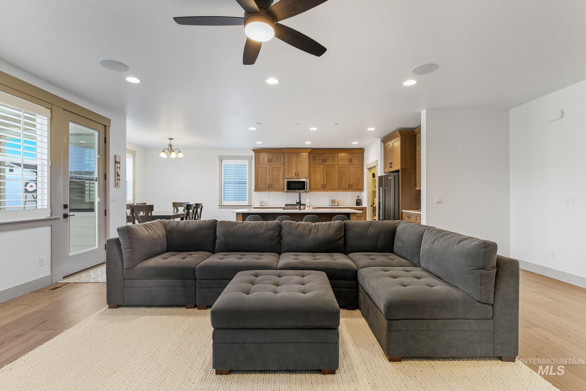Living area with light wood finished floors, recessed lighting, a ceiling fan, and a chandelier
