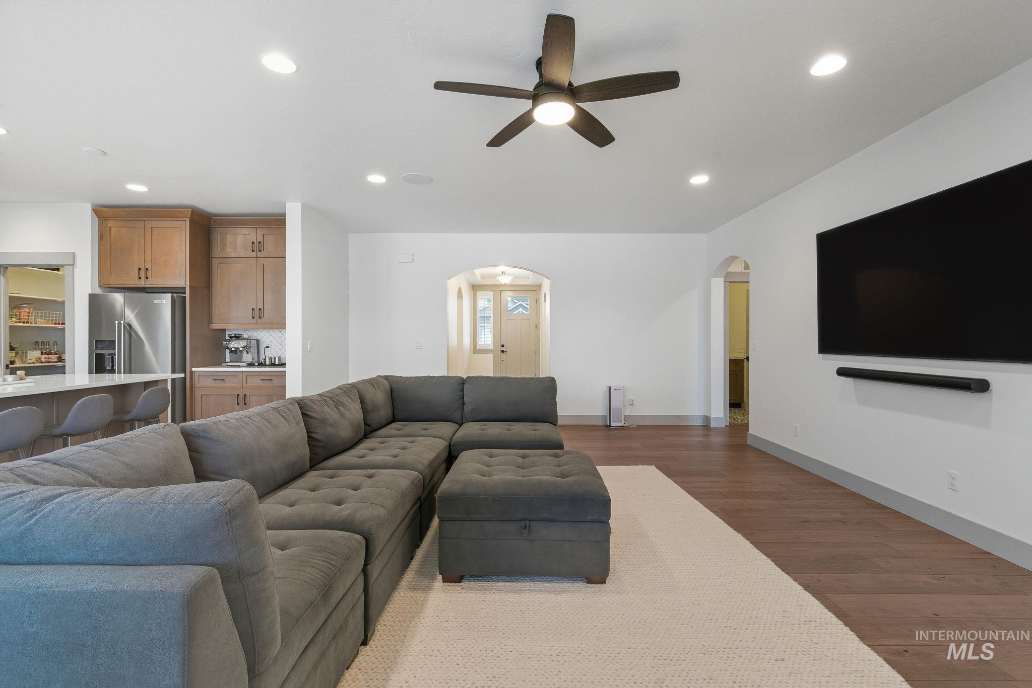 Living area featuring recessed lighting, wood finished floors, arched walkways, and a ceiling fan