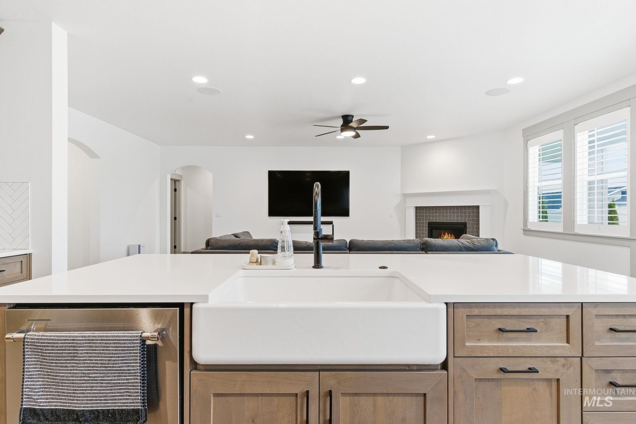 Kitchen featuring a fireplace, open floor plan, recessed lighting, a ceiling fan, and light stone countertops