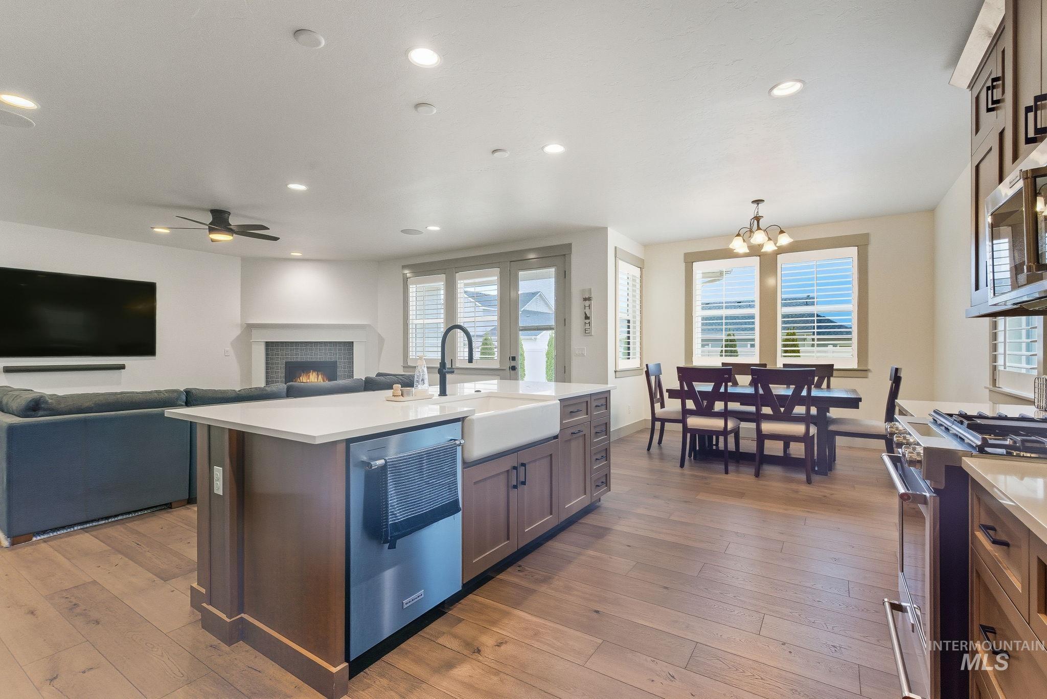 Kitchen featuring a warm lit fireplace, pendant lighting, stainless steel appliances, dark wood finished floors, and recessed lighting