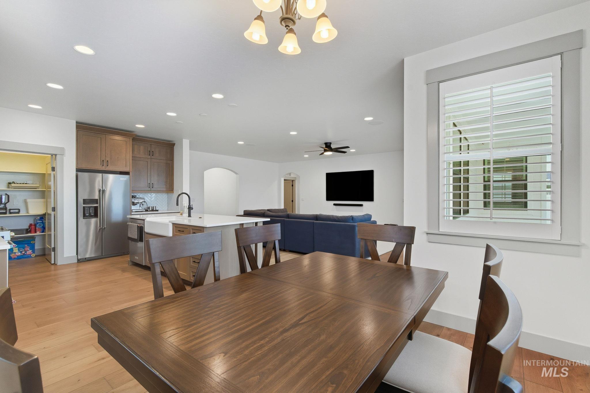 Dining room with arched walkways, a chandelier, light wood-style flooring, recessed lighting, and a ceiling fan
