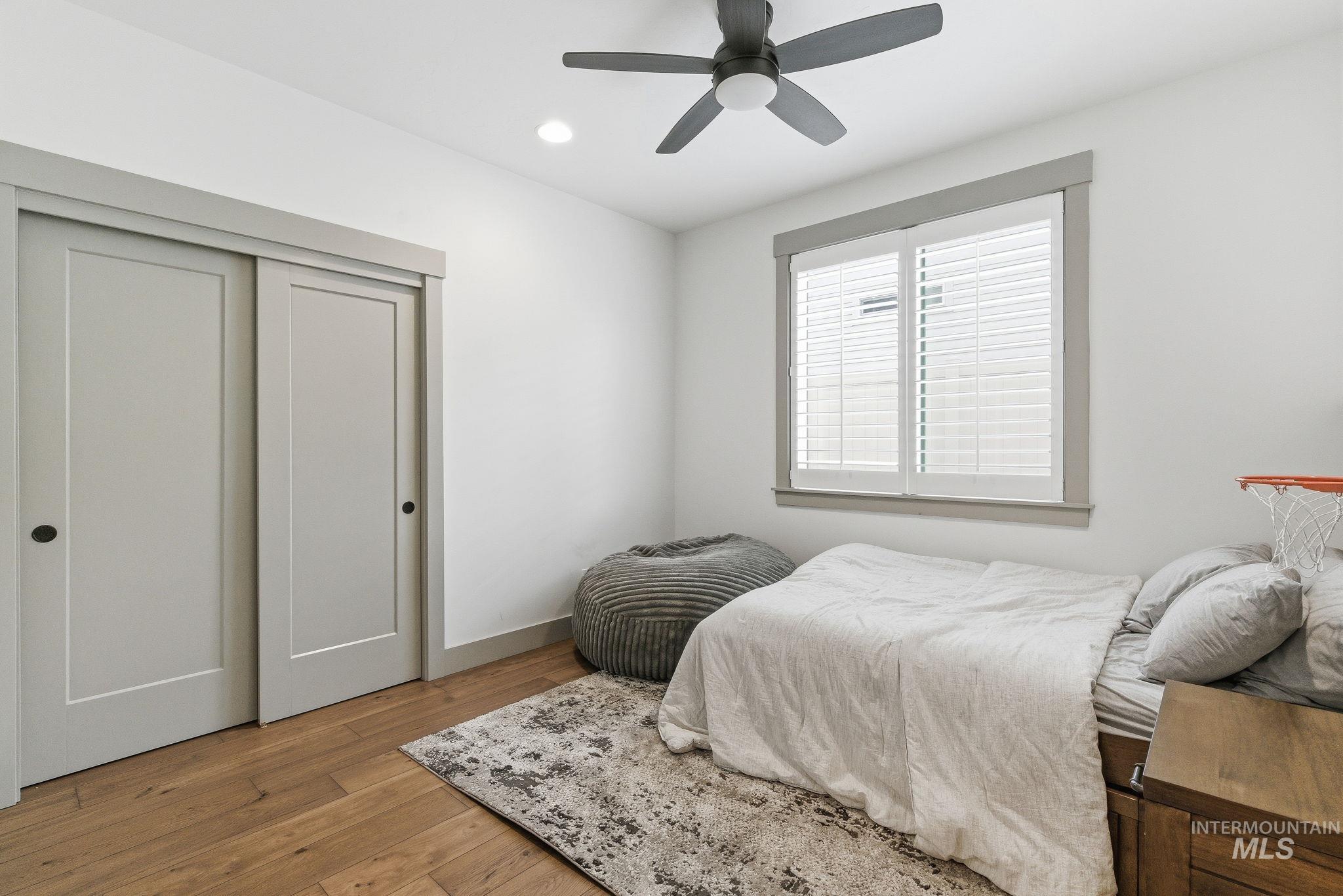 Bedroom with light wood finished floors, a closet, a ceiling fan, and recessed lighting