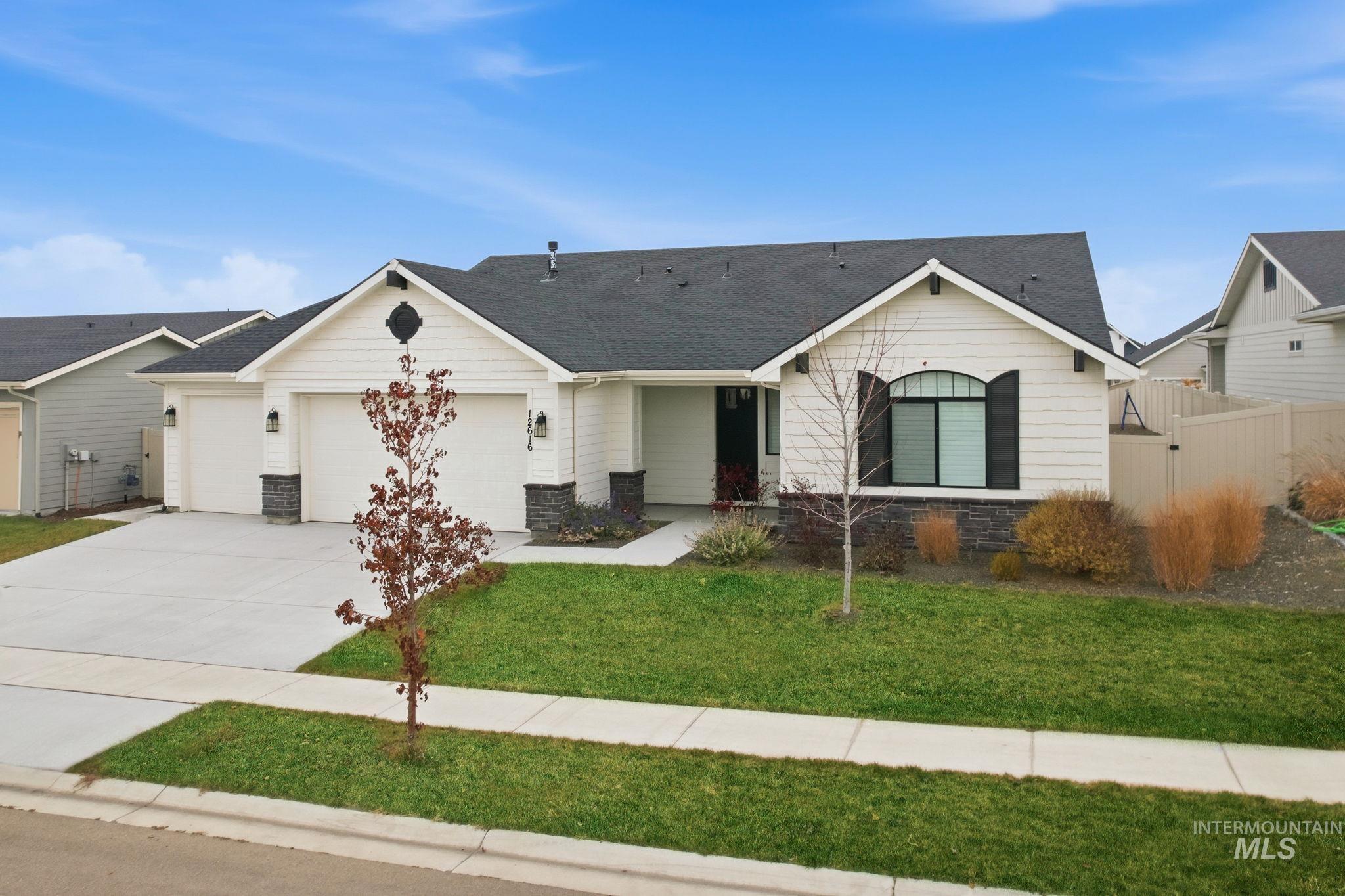 Ranch-style house with driveway, a shingled roof, stone siding, and a garage
