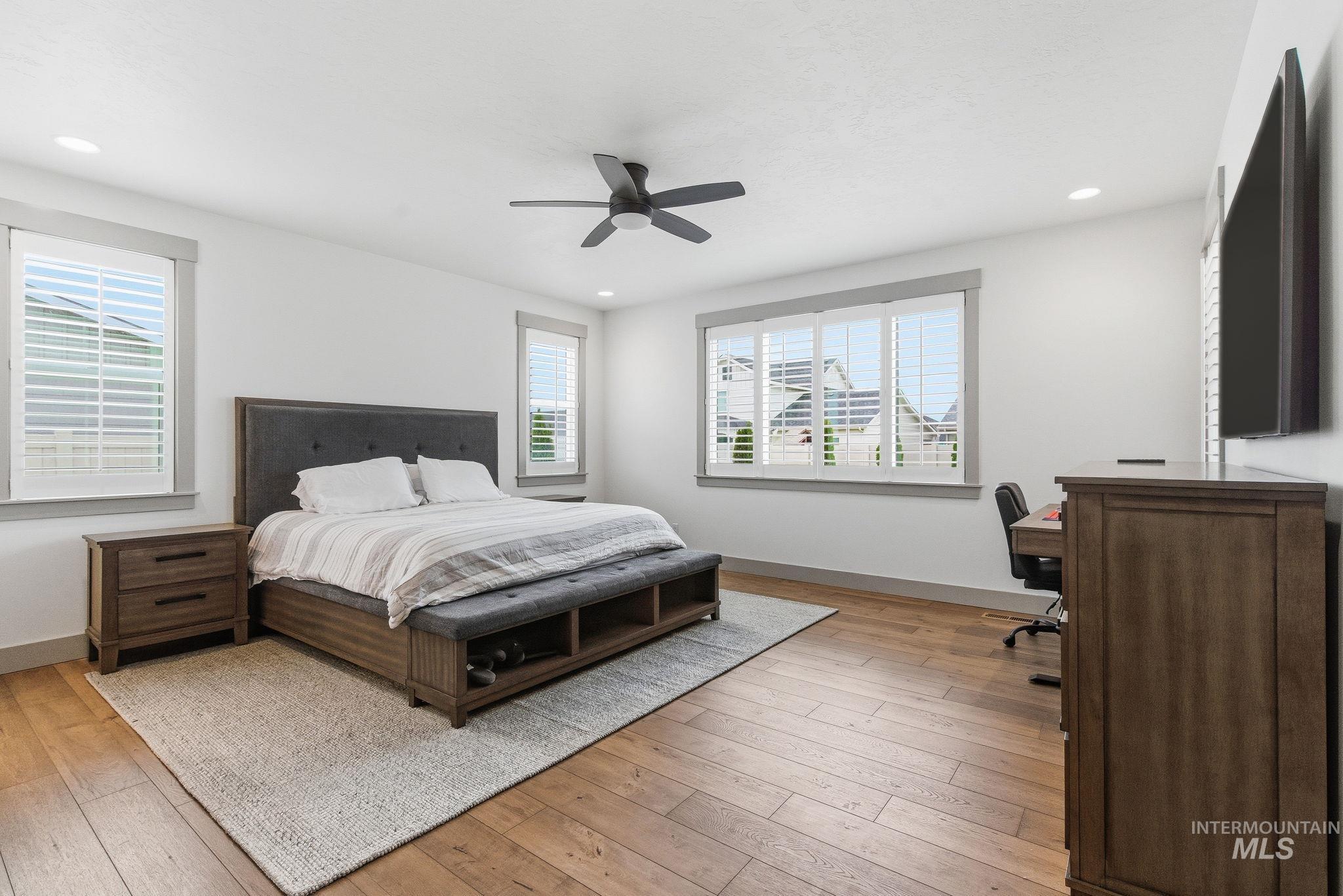 Bedroom with light wood-style floors, ceiling fan, recessed lighting, and a desk