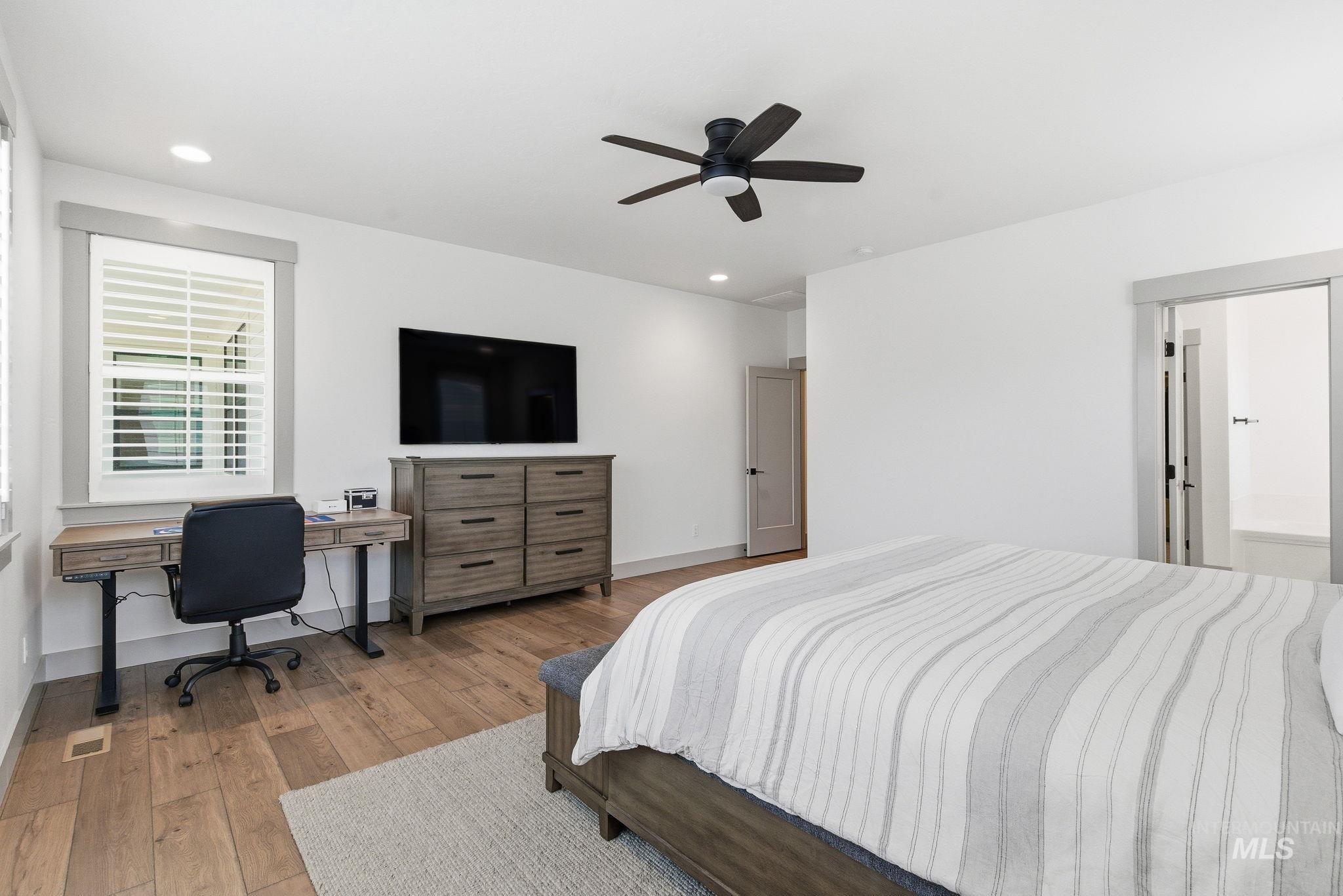 Bedroom featuring light wood-style floors, a ceiling fan, an office area, and recessed lighting
