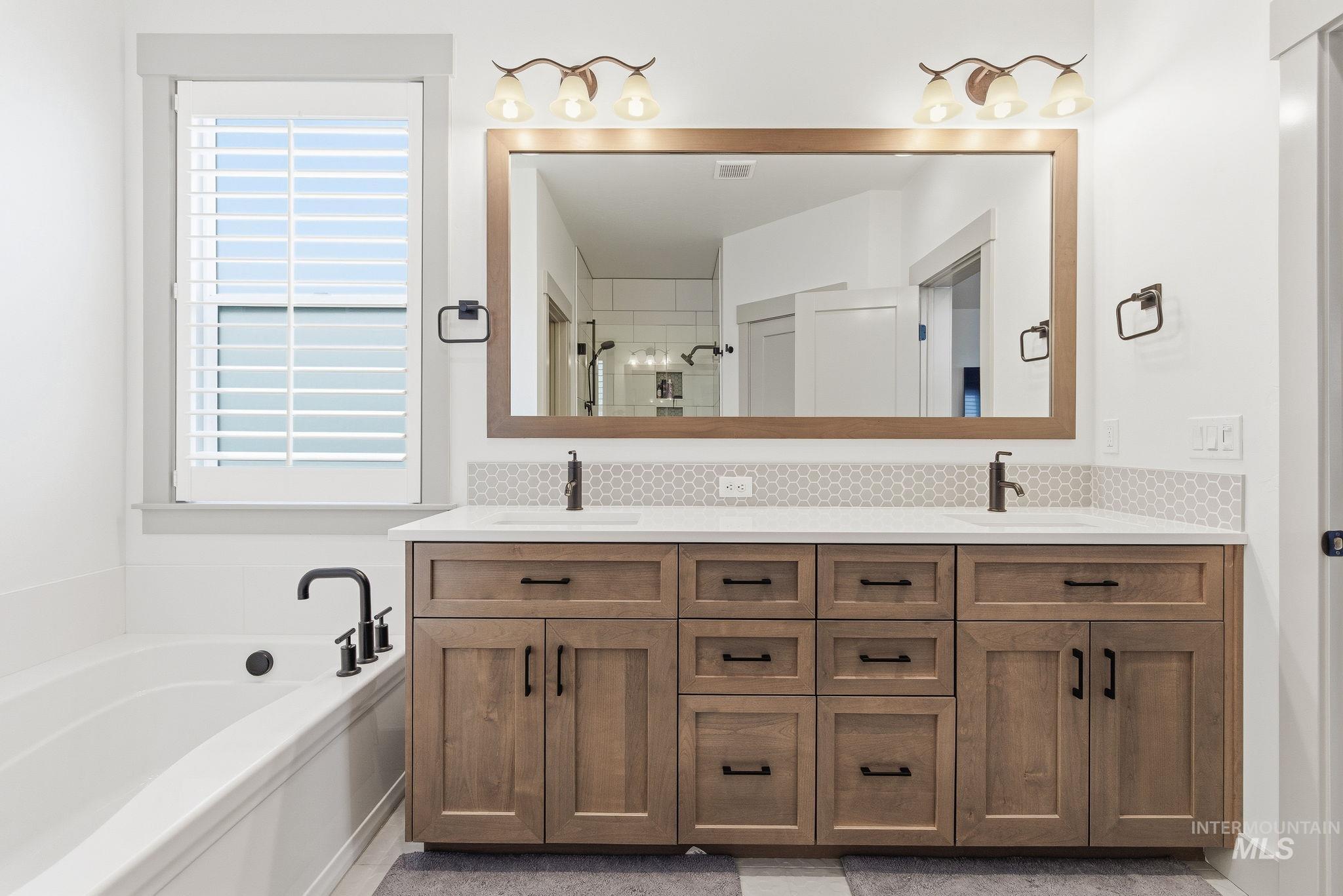 Full bathroom with tasteful backsplash, double vanity, a bath, and a stall shower